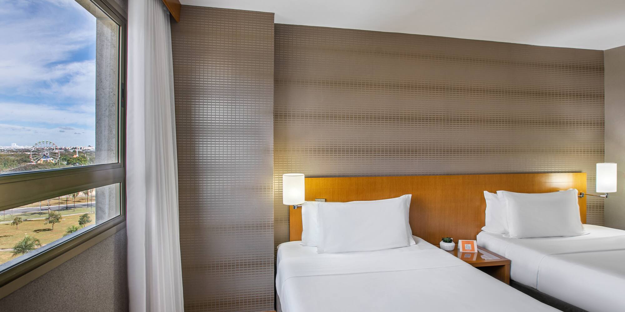Hotel guest room: twin beds, city view with ferris wheel.