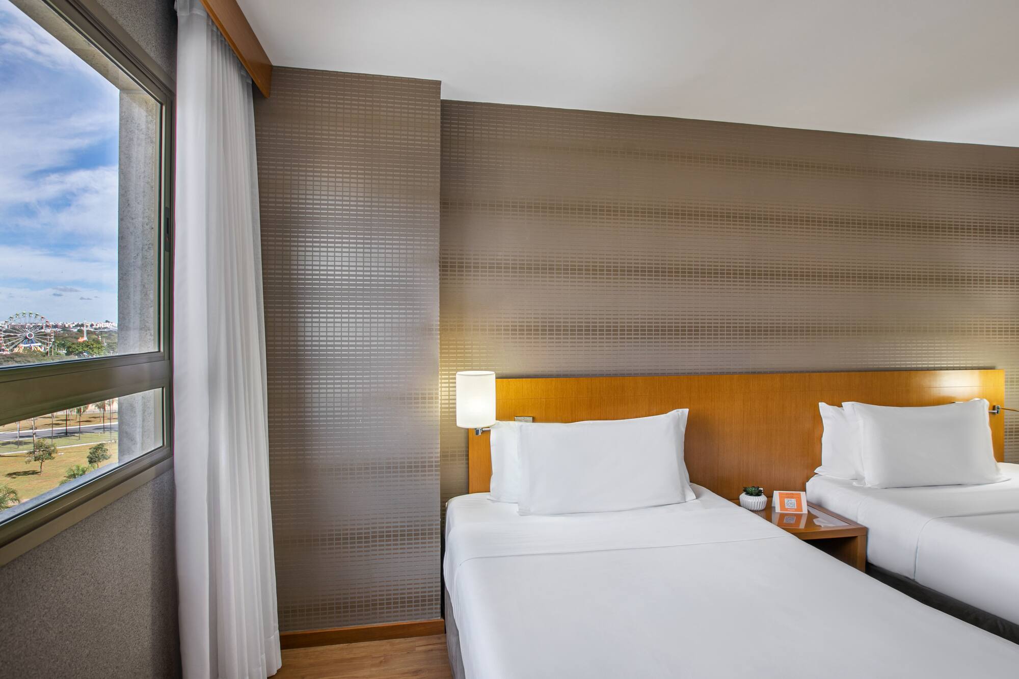 Hotel guest room: twin beds, city view with ferris wheel.