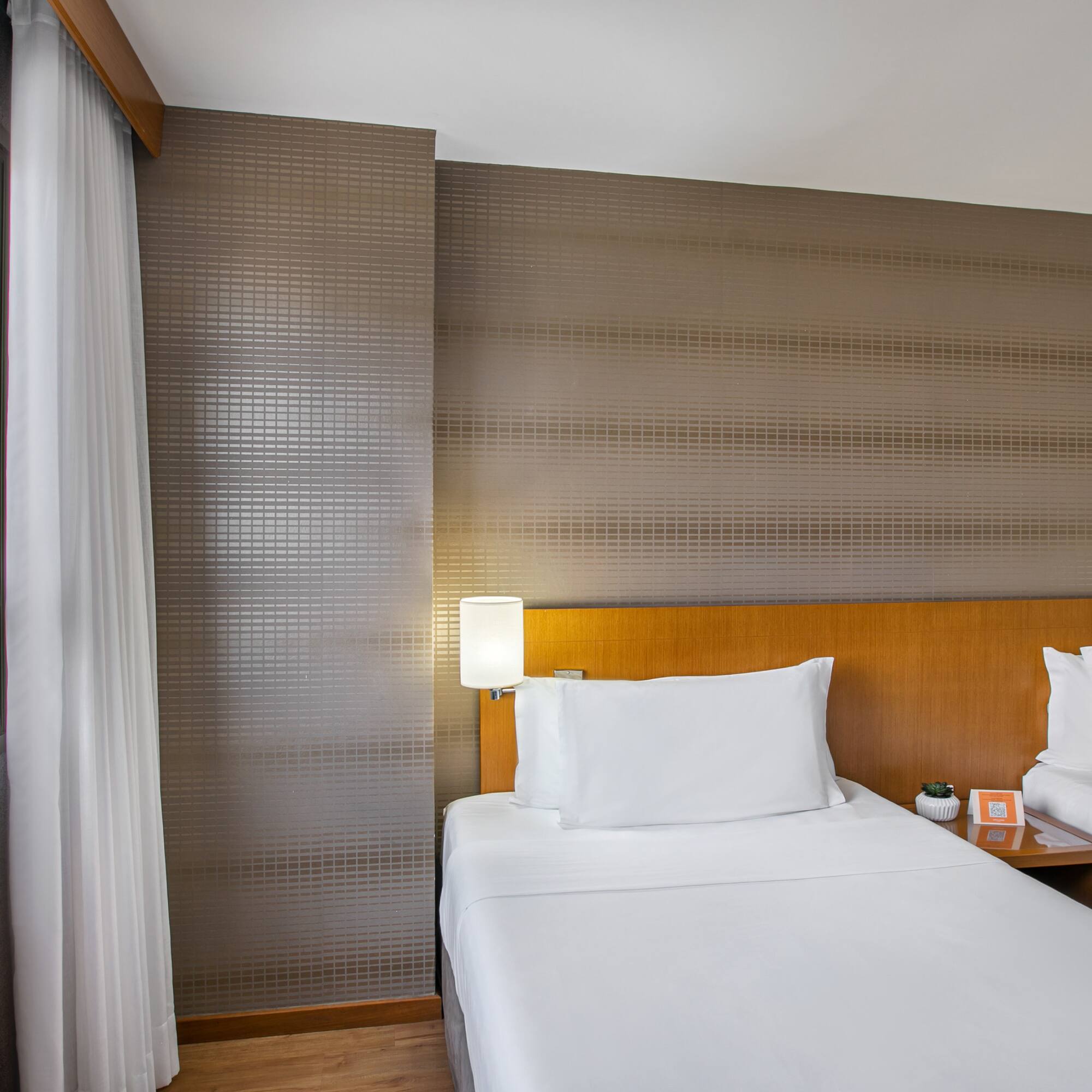 Hotel guest room: twin beds, city view with ferris wheel.