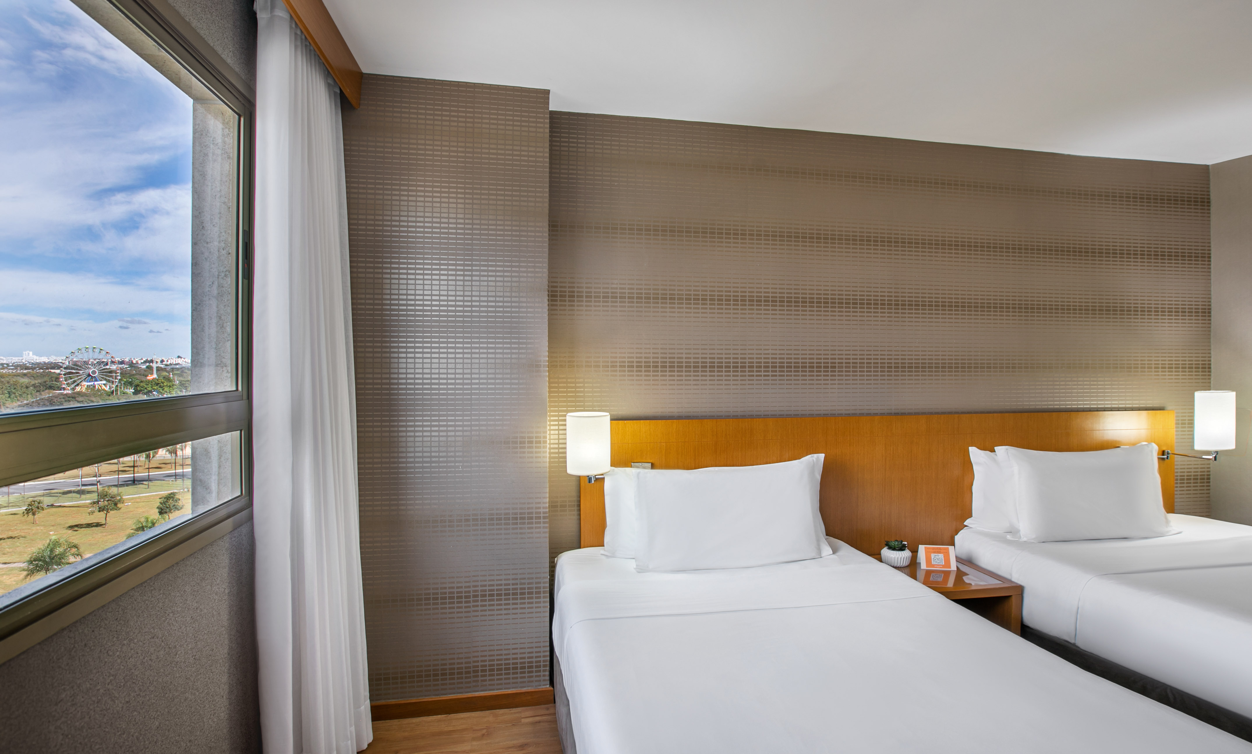 Hotel guest room: twin beds, city view with ferris wheel.