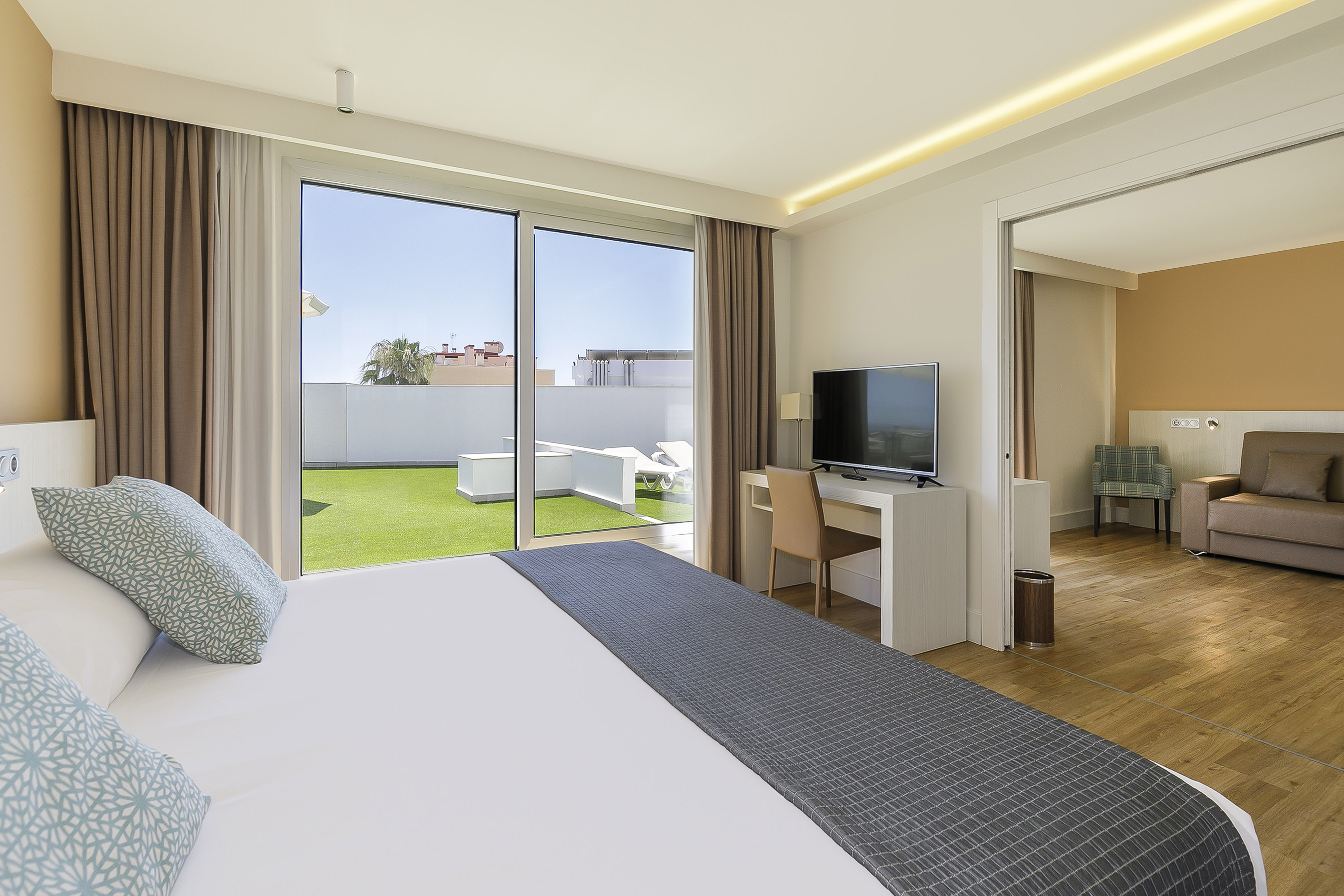 Hotel suite with private terrace, artificial grass, bed, TV, and sun loungers.