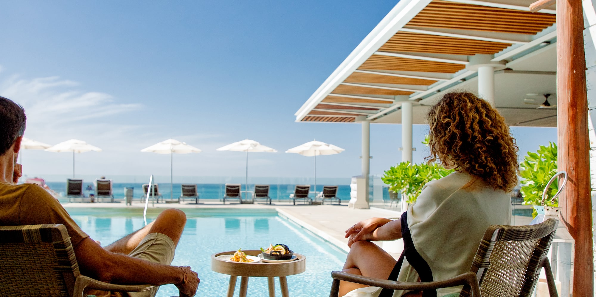 a man and woman sitting on chairs by a pool