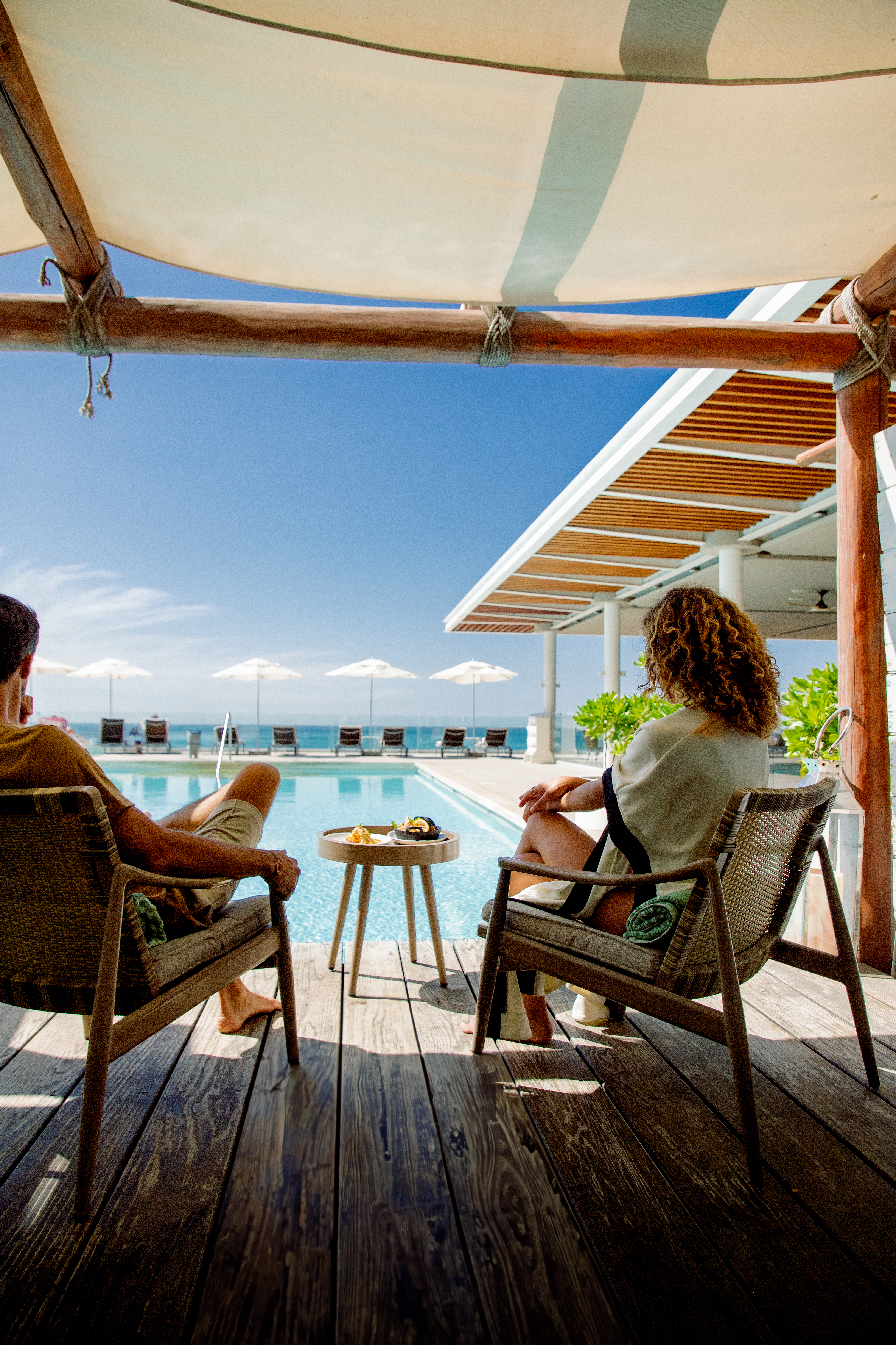 a man and woman sitting on chairs by a pool