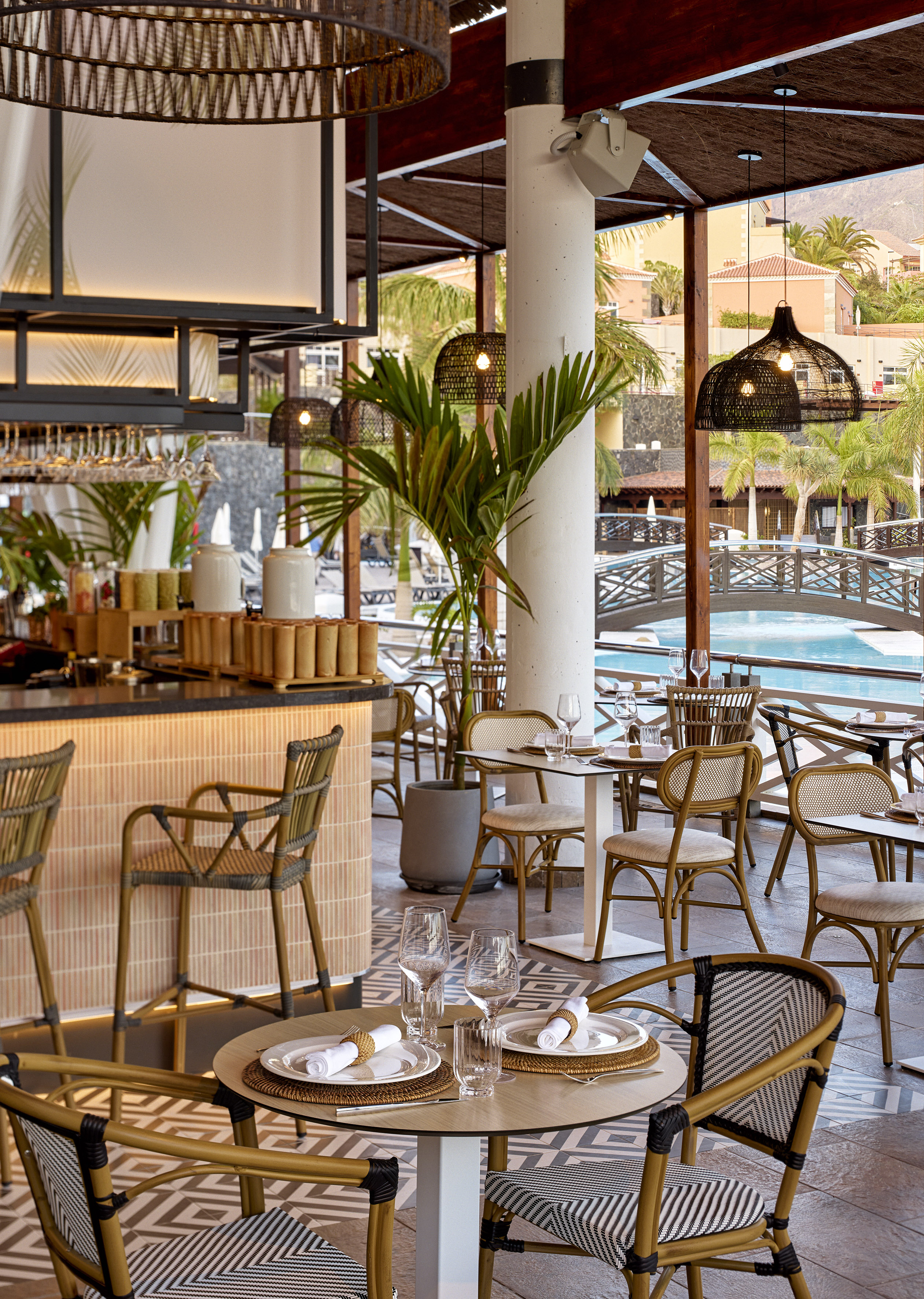 Elegant tropical resort restaurant with wicker furniture and poolside views.