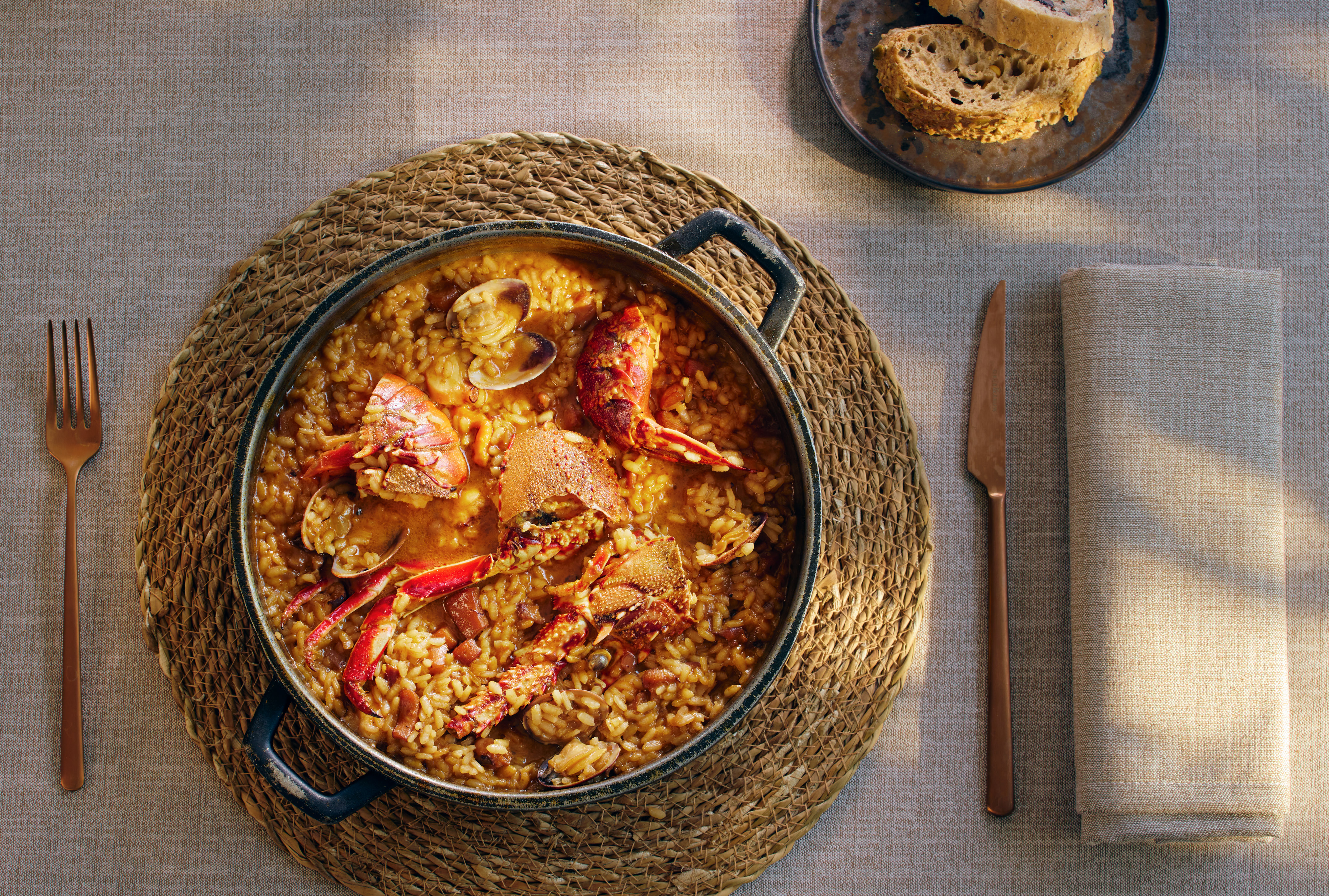 Arroz caldoso de marisco con bogavante y almejas, servido en olla, vista superior.