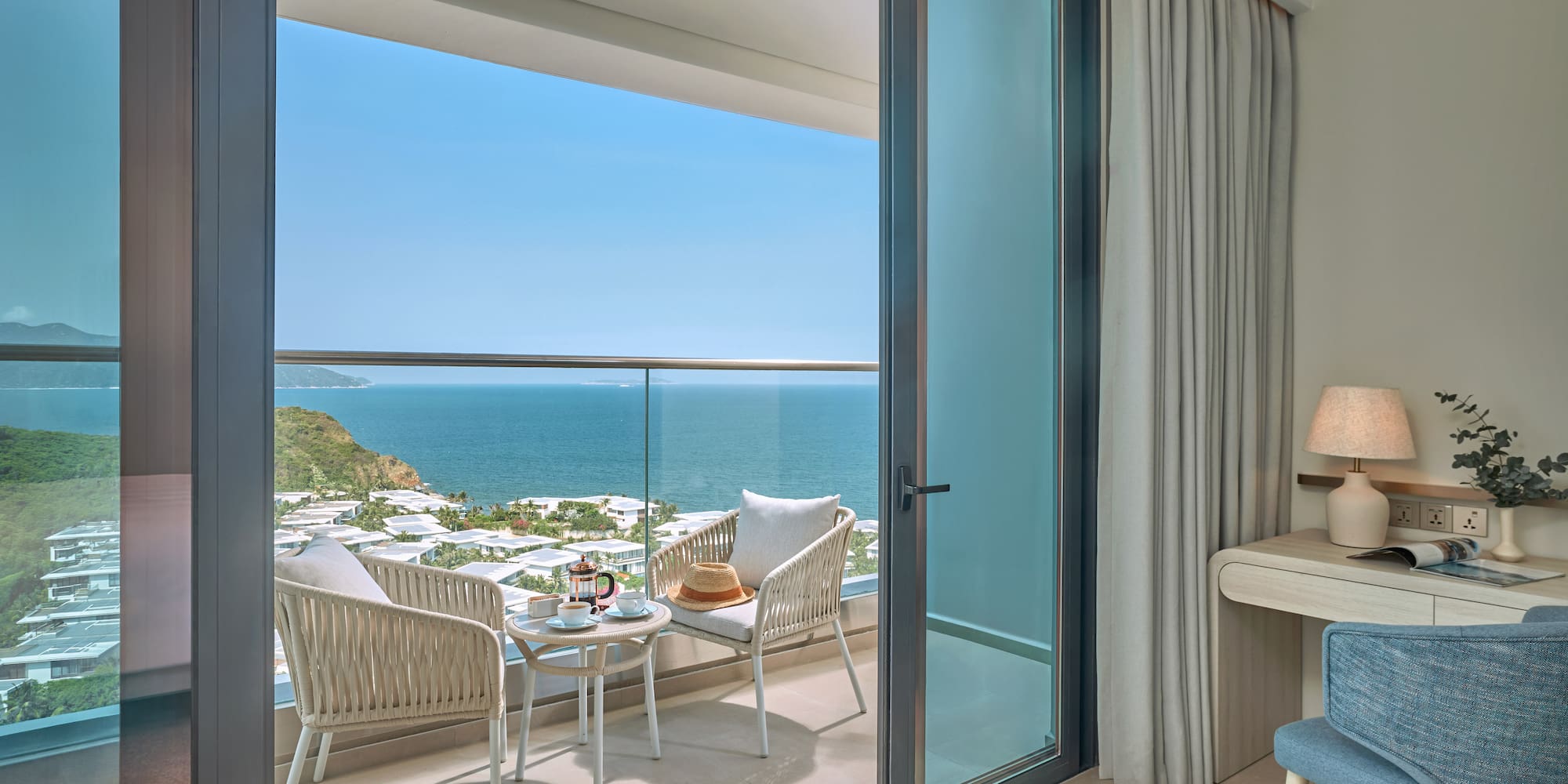 Ocean view balcony with seating, coffee, and coastal resort.