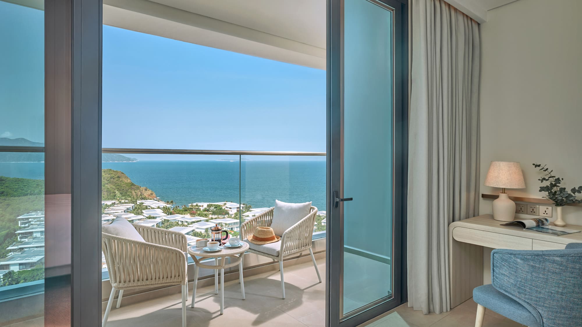 Ocean view balcony with seating, coffee, and coastal resort.