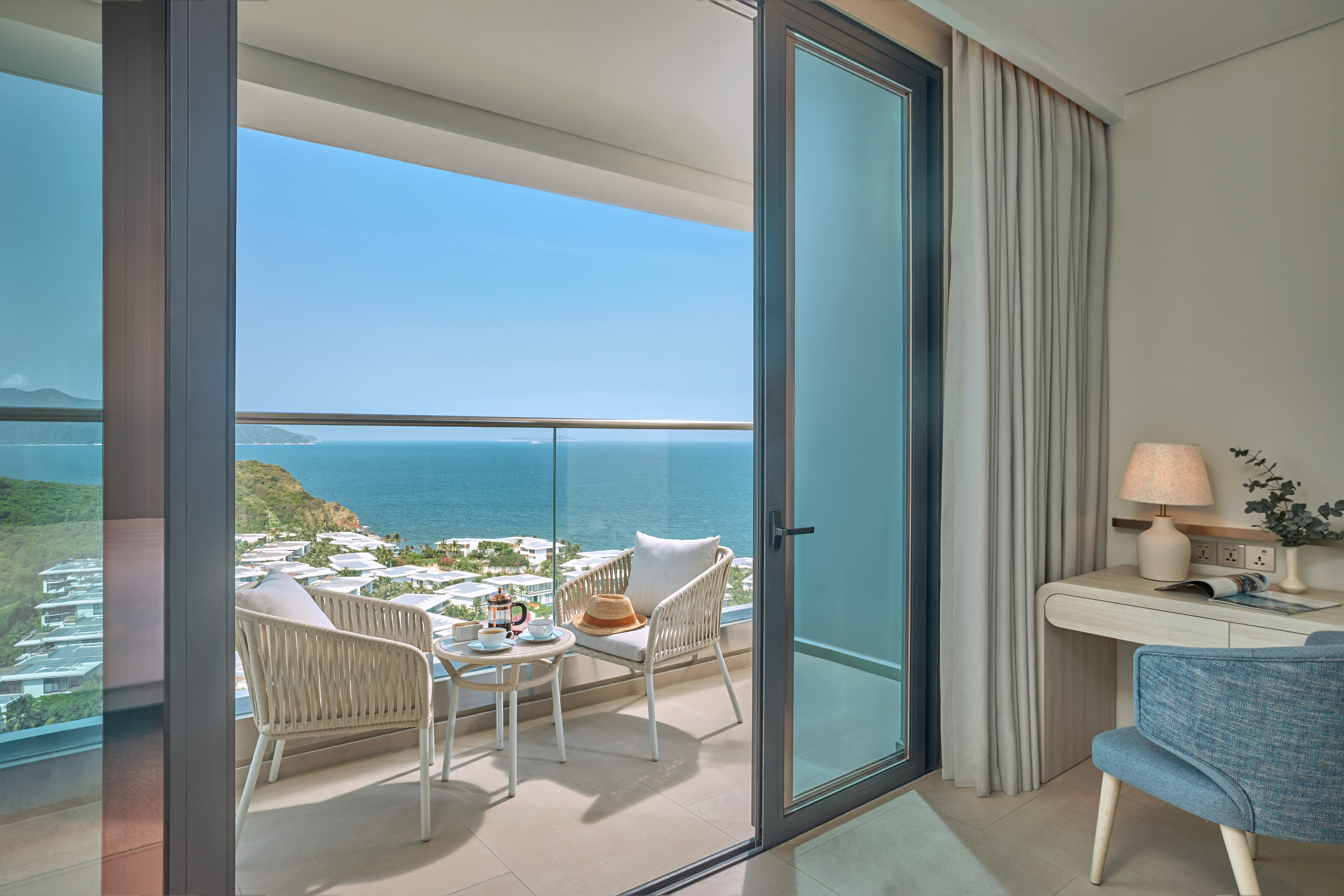 Ocean view balcony with seating, coffee, and coastal resort.