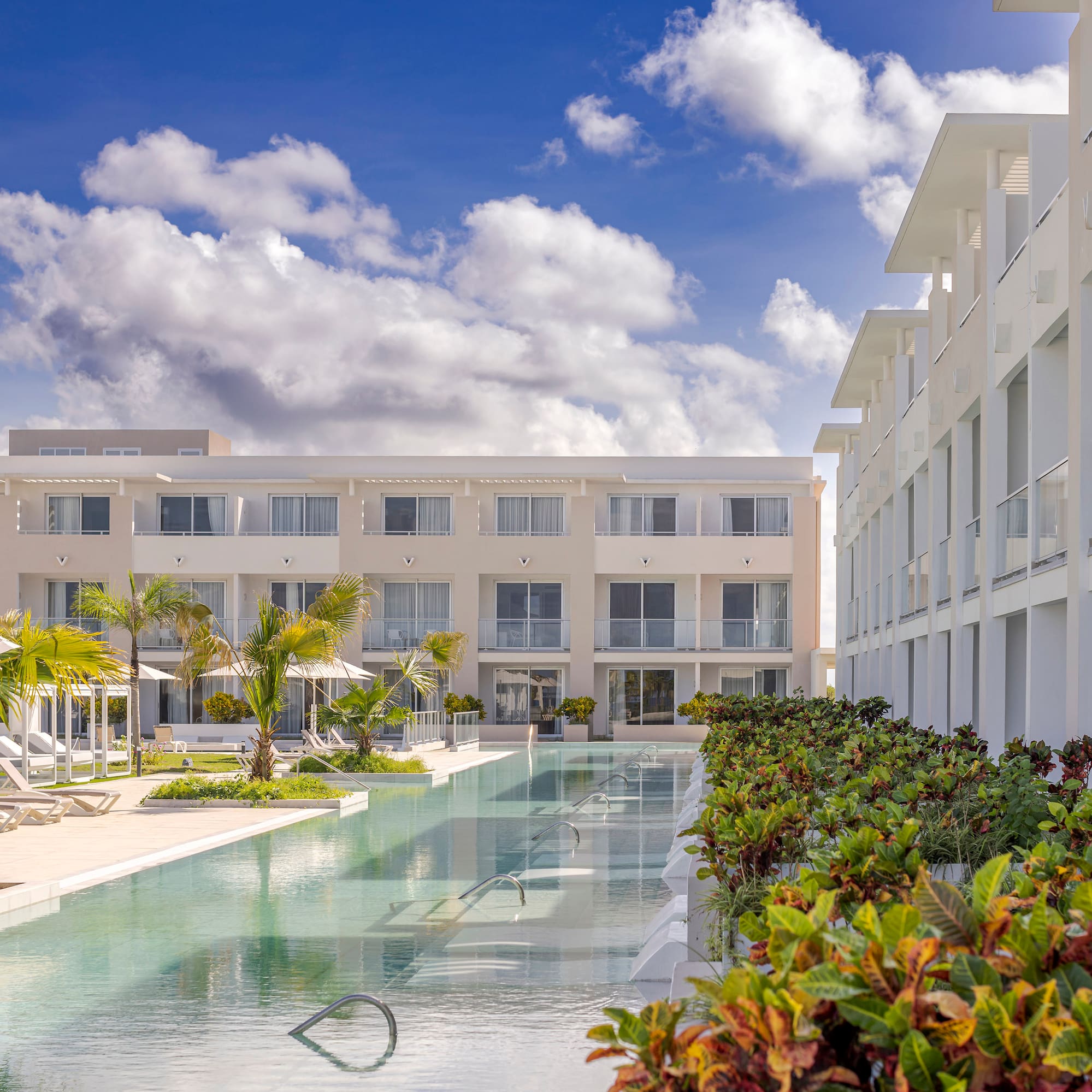 a pool with lounge chairs and trees in front of a building