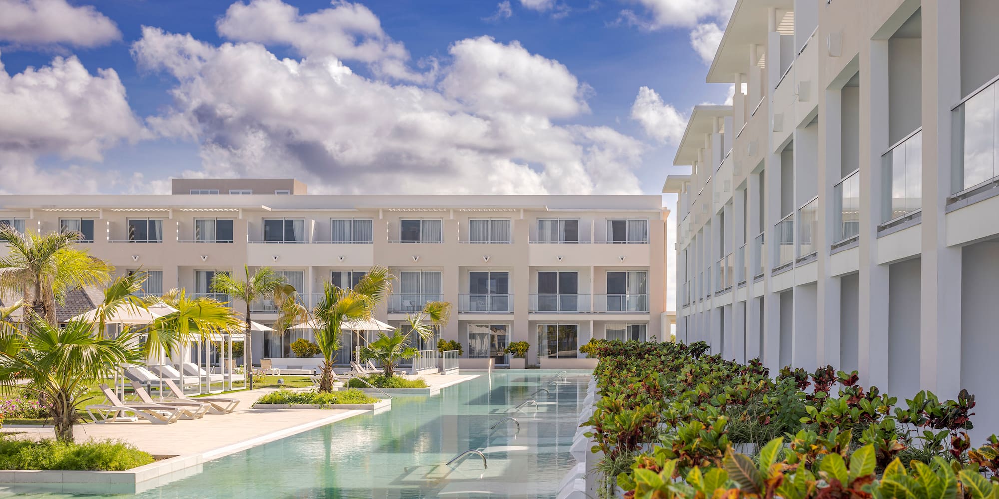 a pool with lounge chairs and trees in front of a building