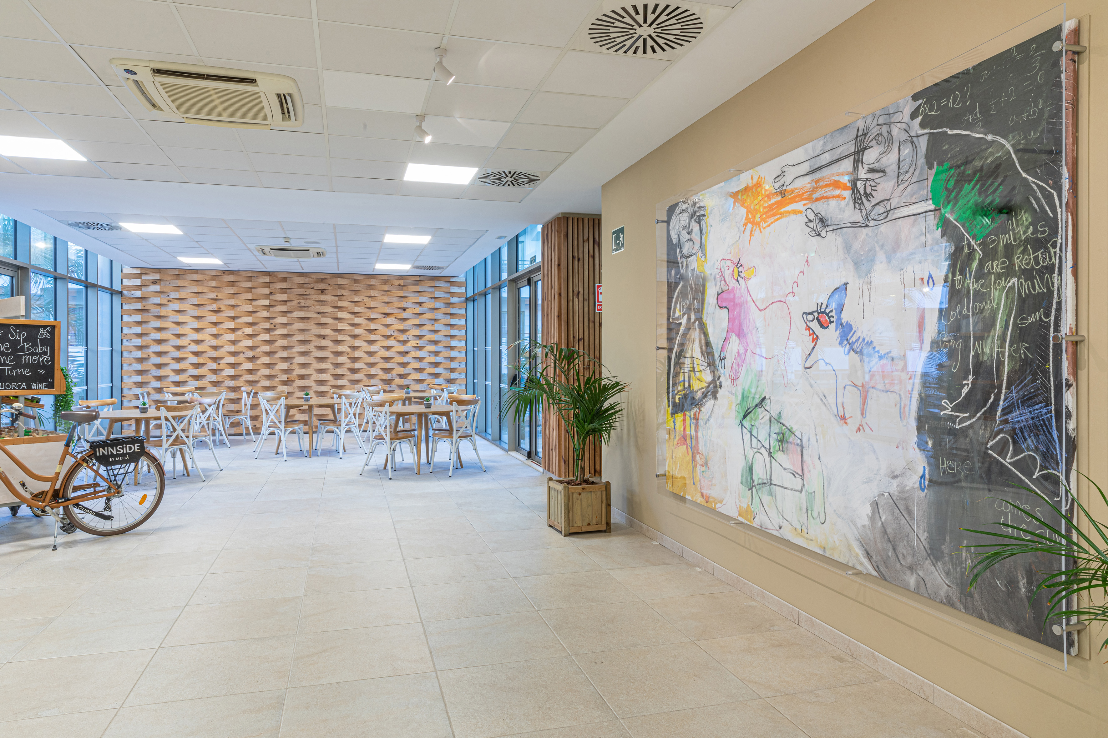 Modern hotel lounge with dining area, wooden wall, and colorful abstract art.