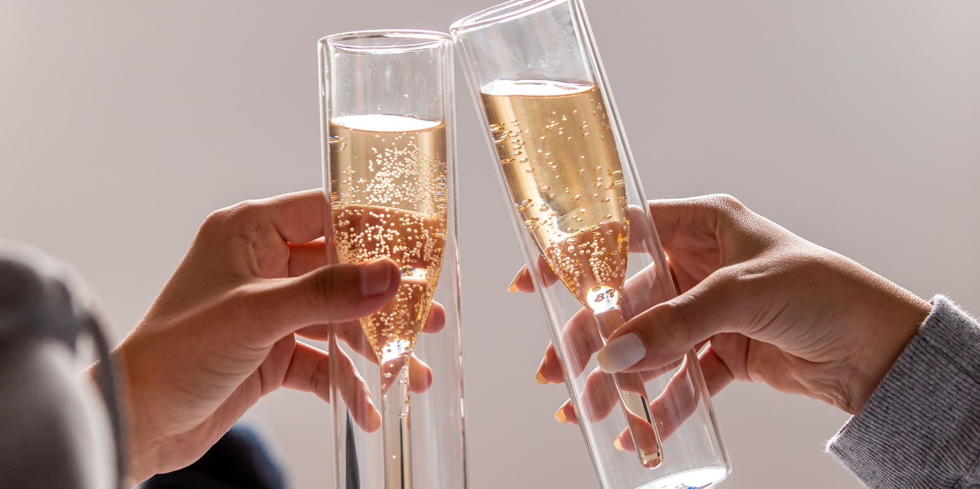 a pair of hands holding glasses of champagne