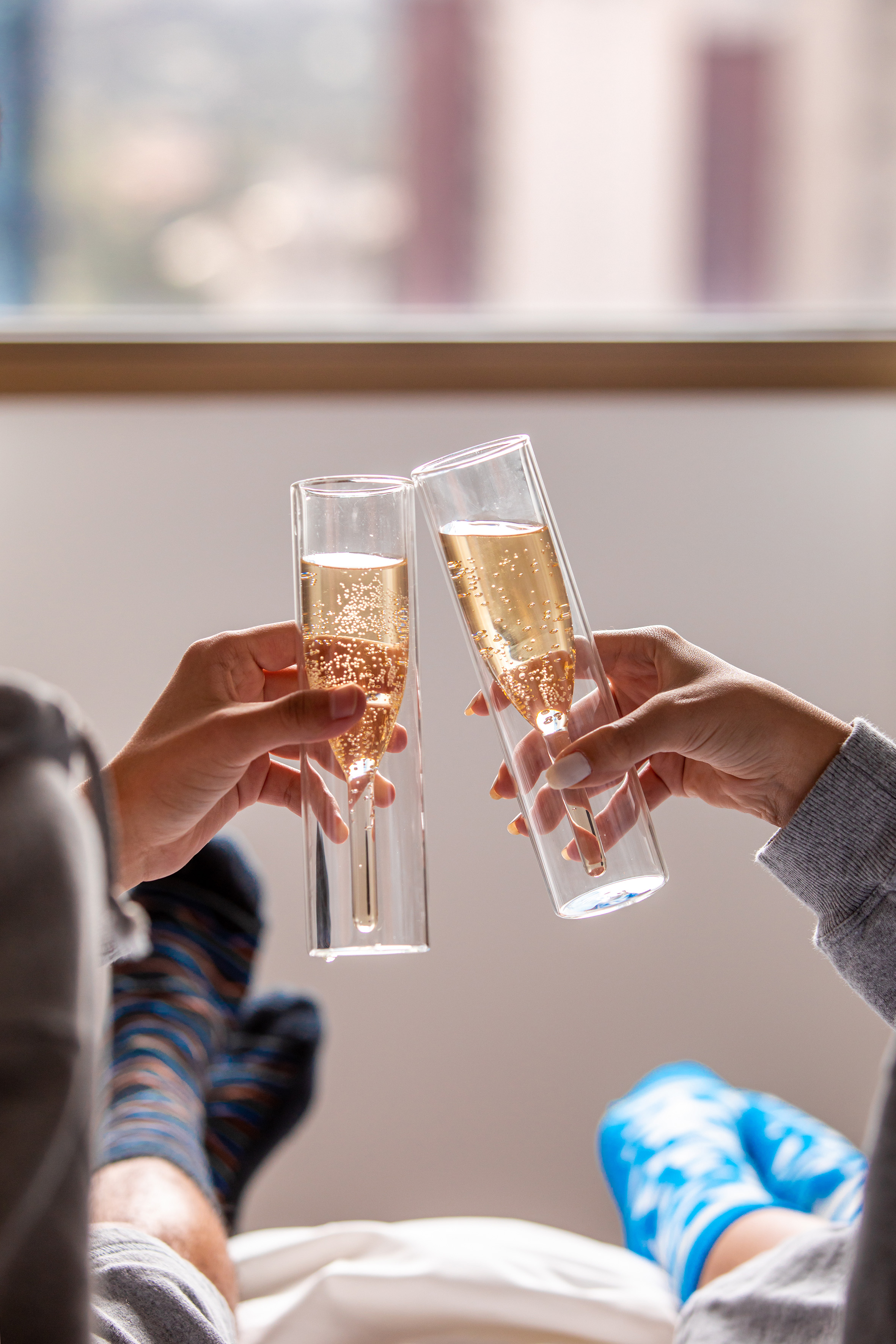 Hands toasting modern champagne flutes with sparkling wine in a relaxed setting.