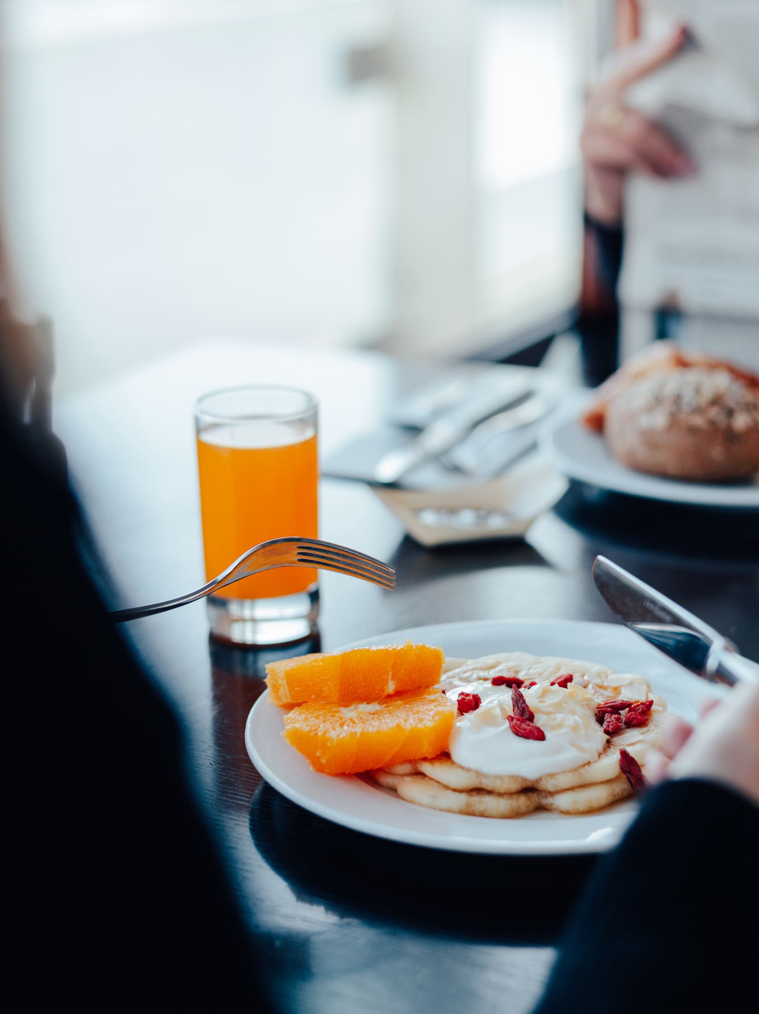 Pancakes with orange slices, goji berries, and orange juice at breakfast.