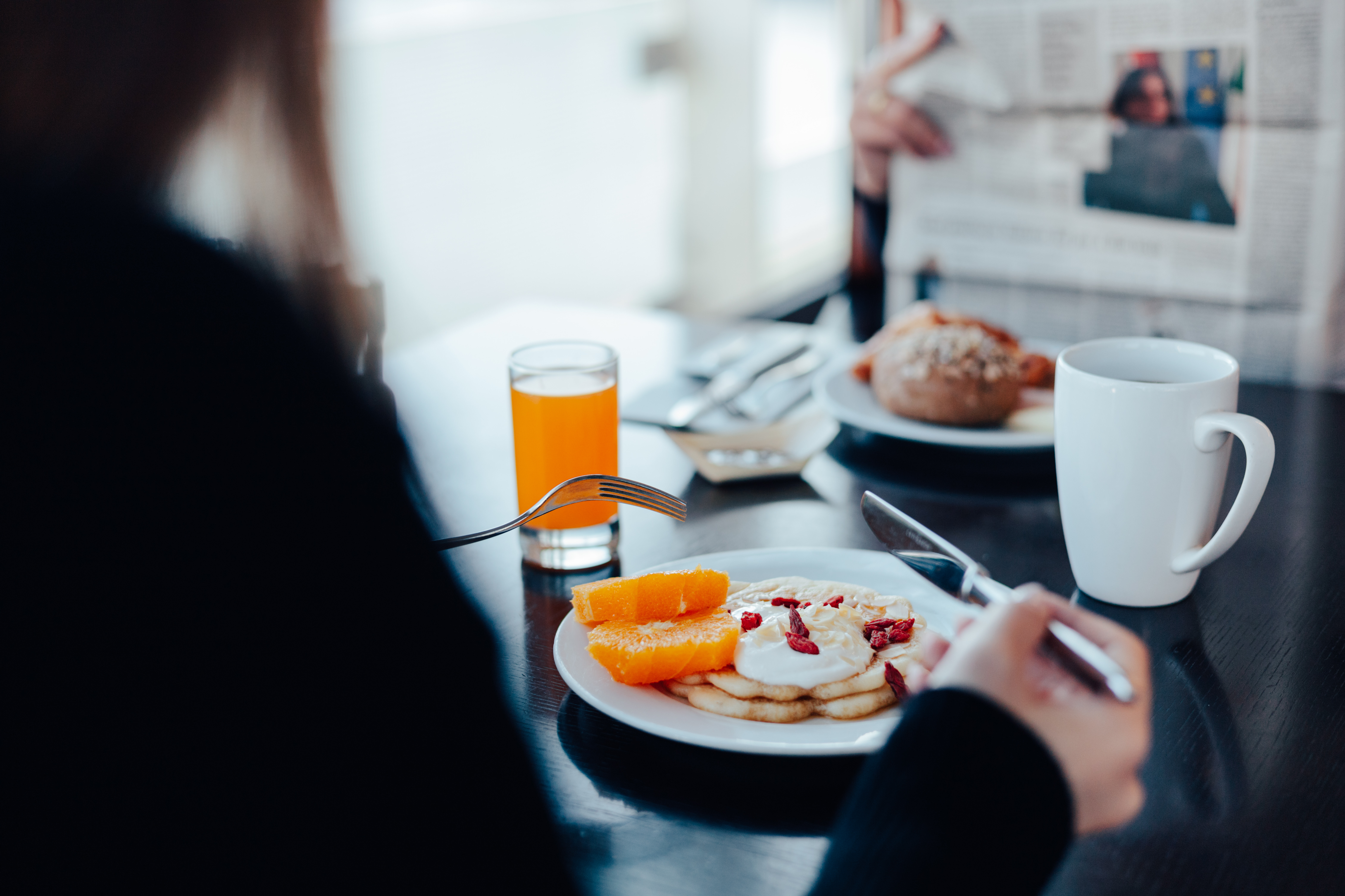 Pancakes with orange slices, goji berries, and orange juice at breakfast.