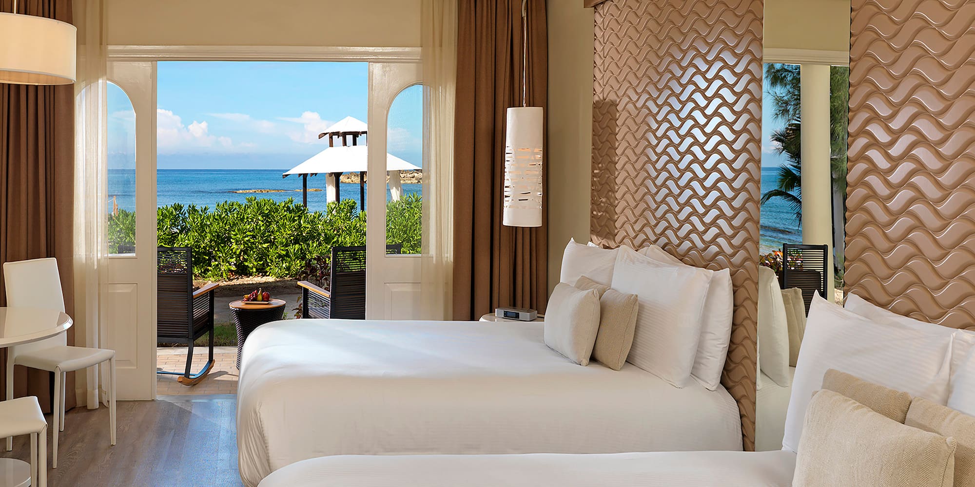 two beds in a room with a view of the ocean