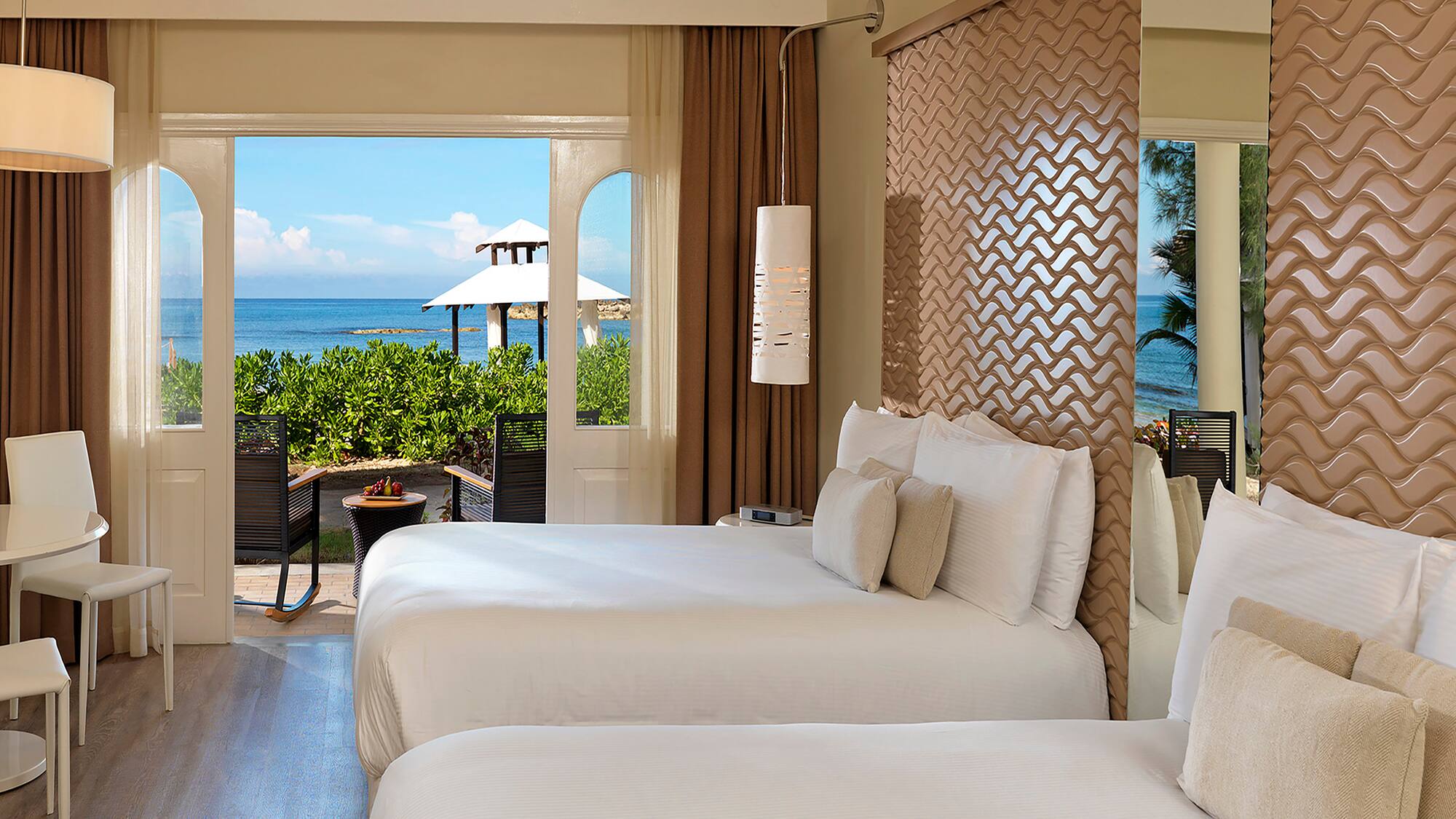 two beds in a room with a view of the ocean