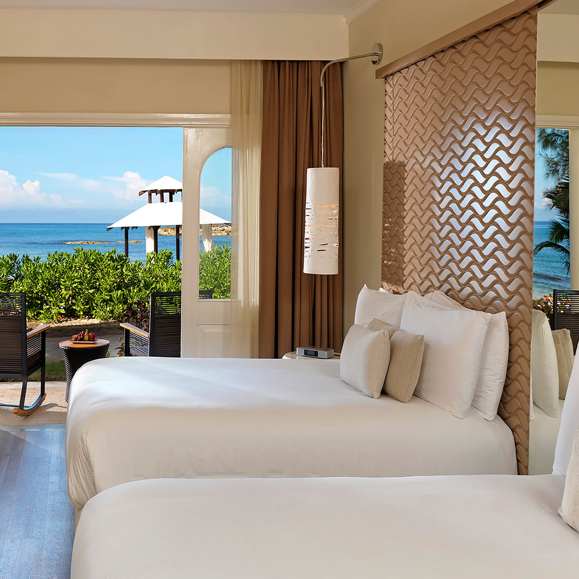 two beds in a room with a view of the ocean