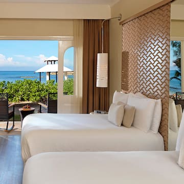 two beds in a room with a view of the ocean