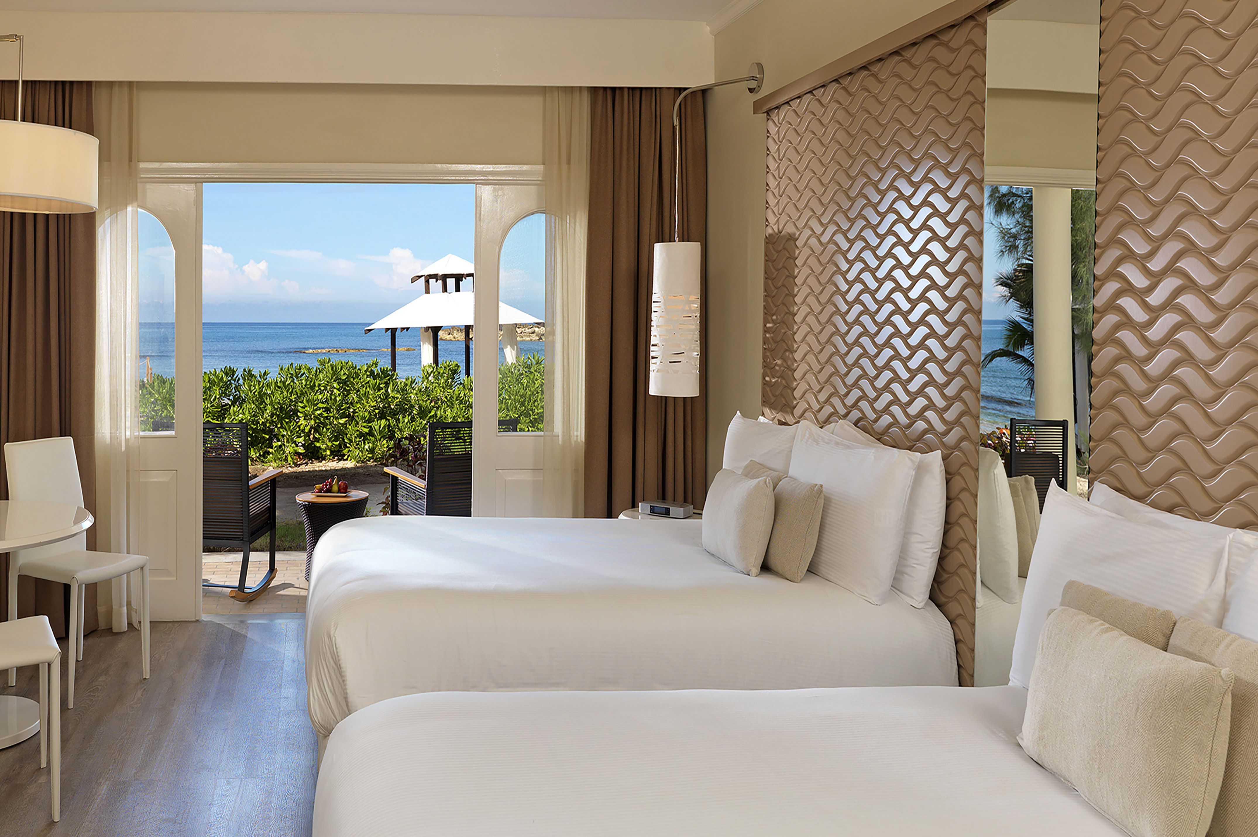two beds in a room with a view of the ocean