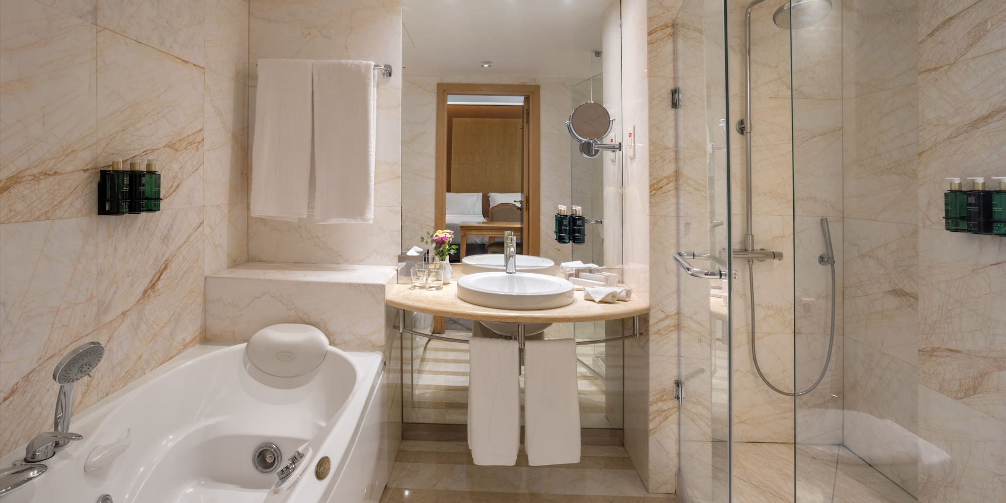 Luxury hotel bathroom: marble, bathtub, glass shower, modern vanity.