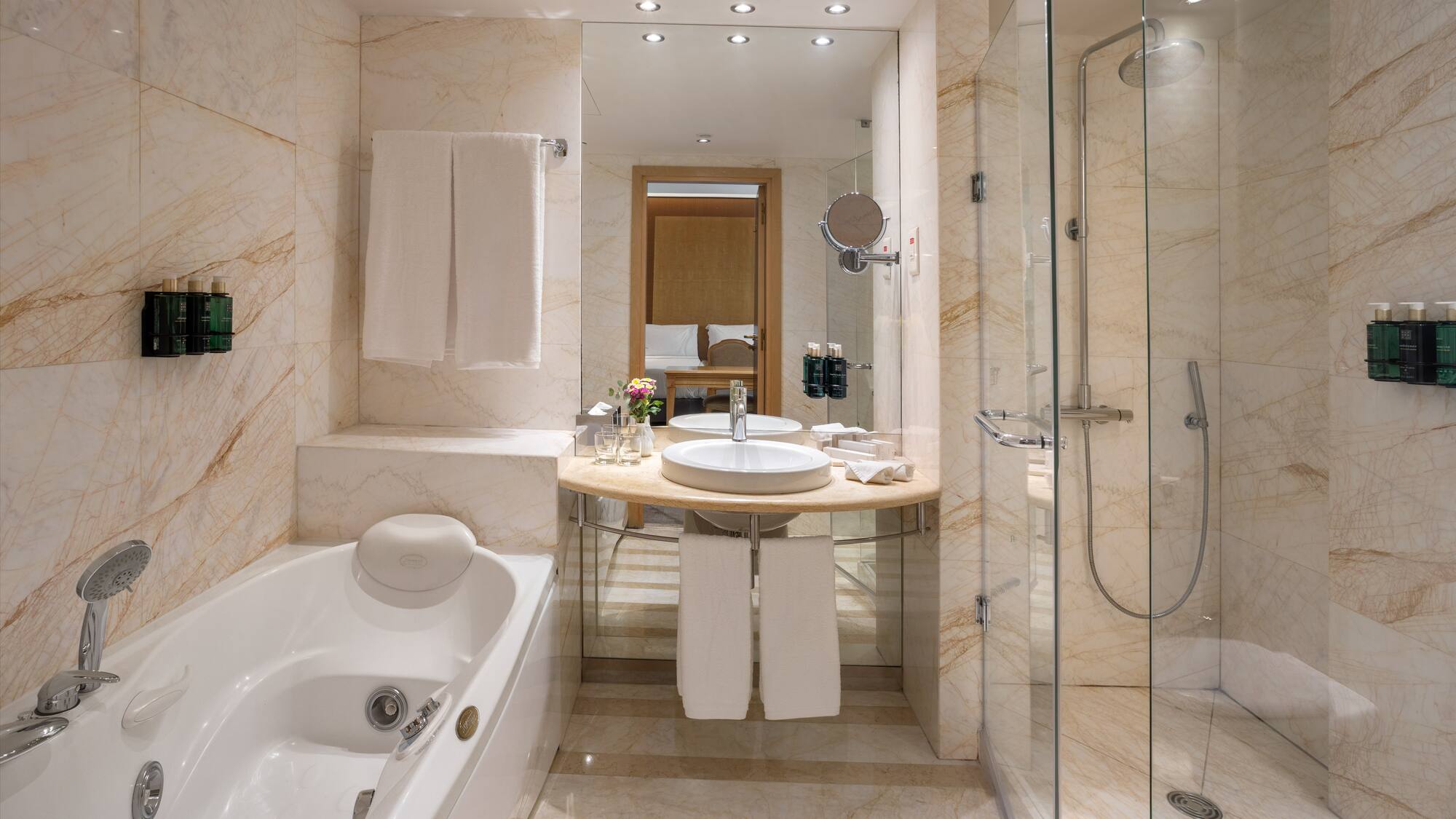 Luxury hotel bathroom: marble, bathtub, glass shower, modern vanity.