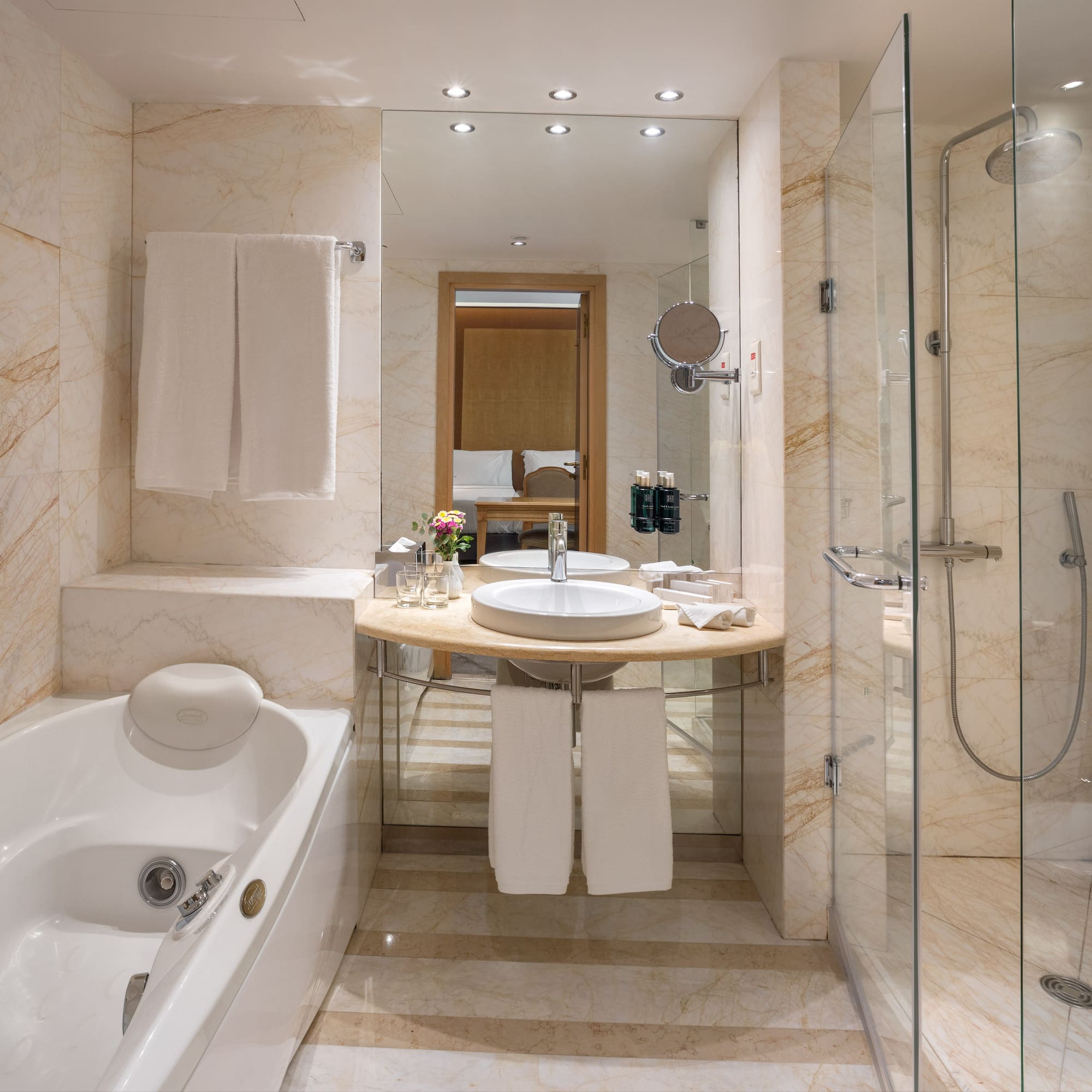 Luxury hotel bathroom: marble, bathtub, glass shower, modern vanity.