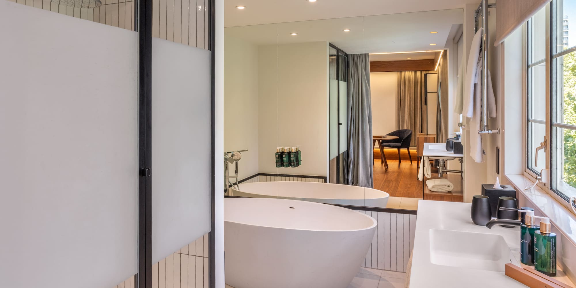 Modern hotel bathroom with freestanding tub, walk-in shower, and double vanity.