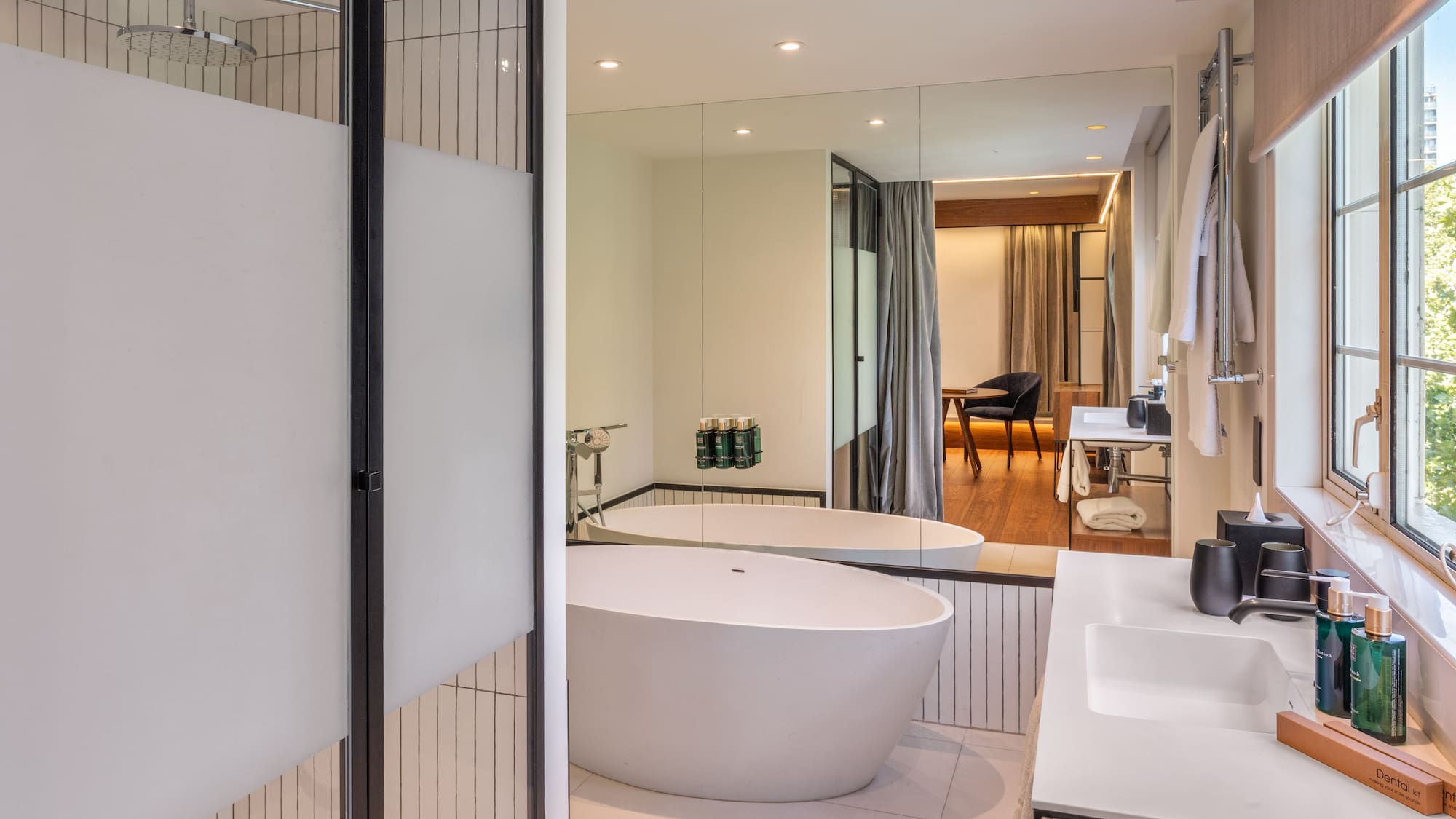 Modern hotel bathroom with freestanding tub, walk-in shower, and double vanity.