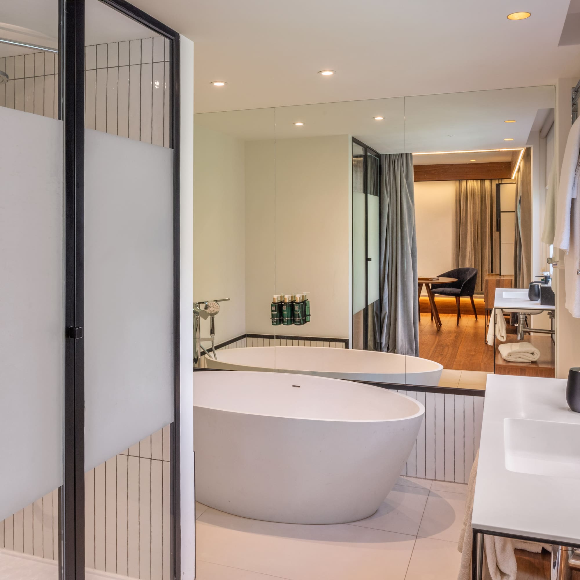 Modern hotel bathroom with freestanding tub, walk-in shower, and double vanity.