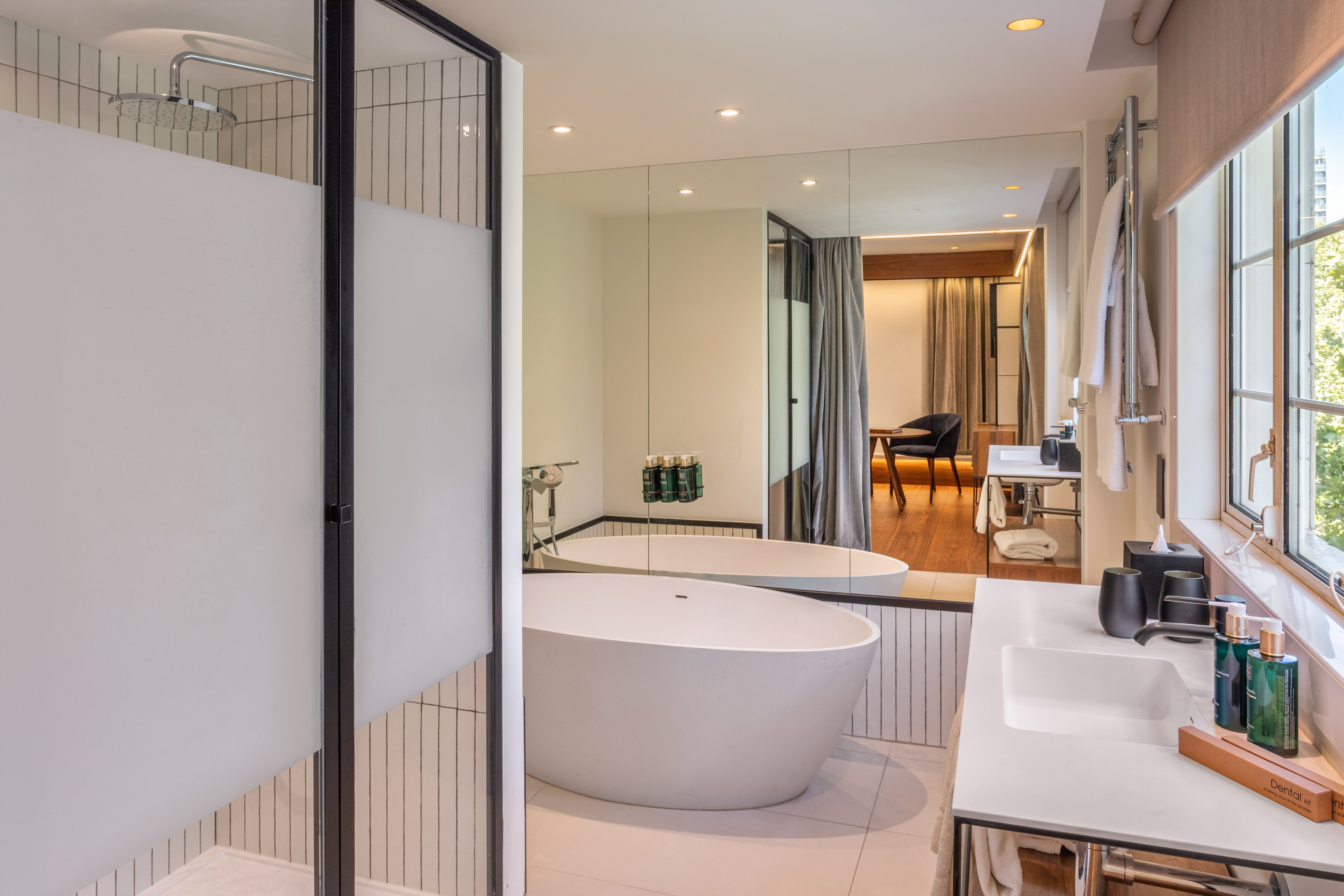 Modern hotel bathroom with freestanding tub, walk-in shower, and double vanity.