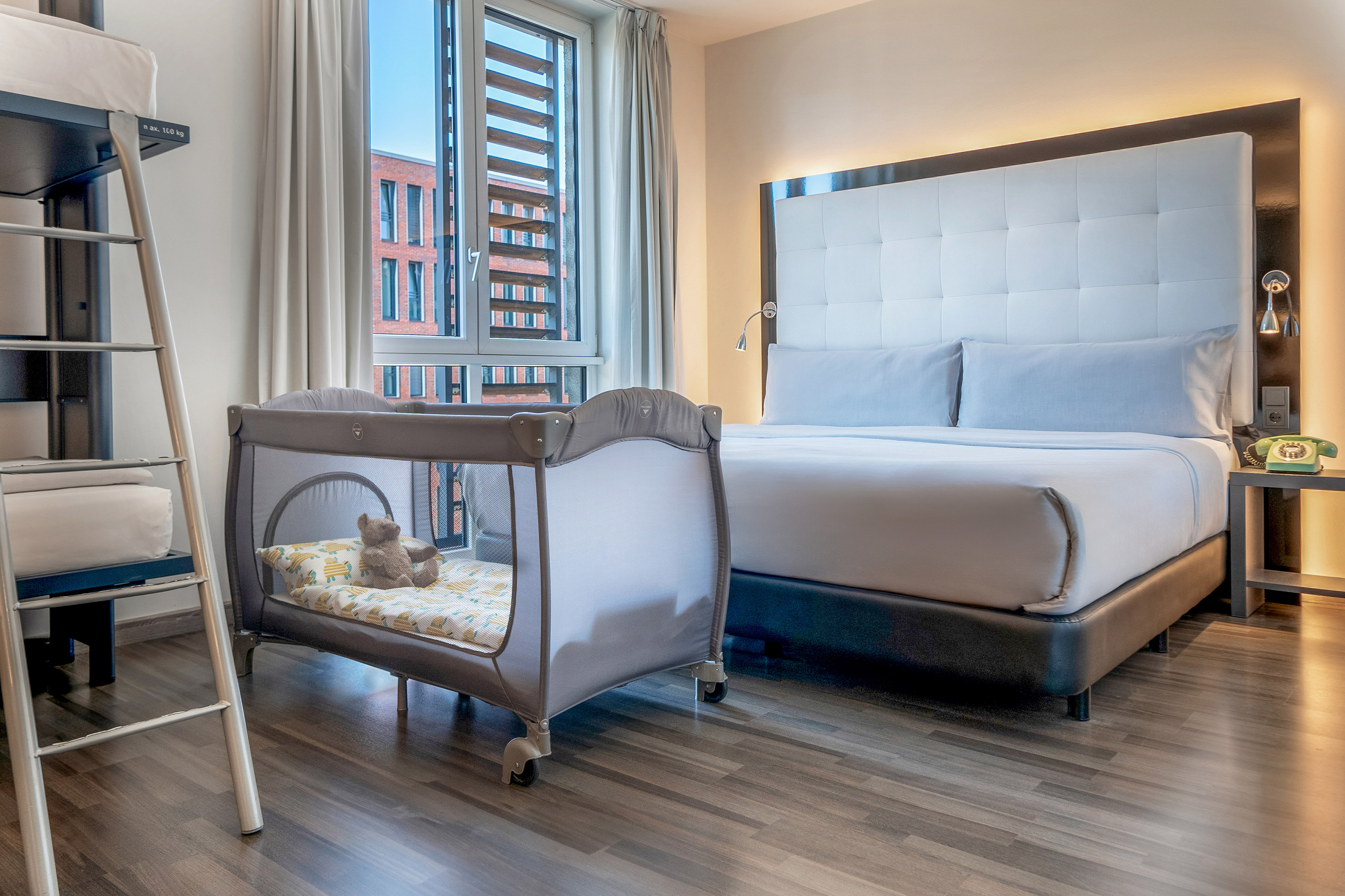 Family hotel room with large bed, baby travel crib, and bunk bed.