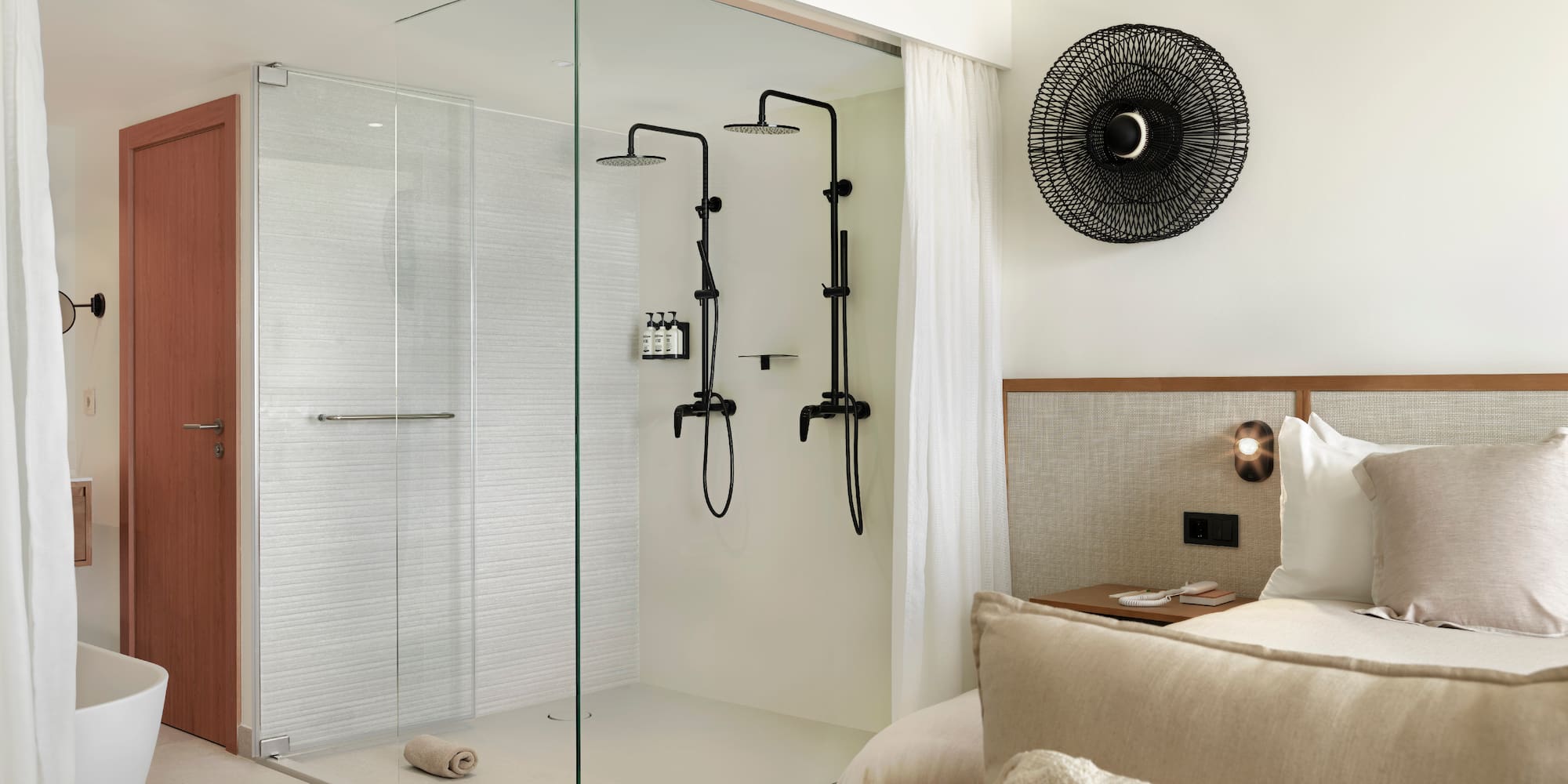 a room with a glass shower and a bed