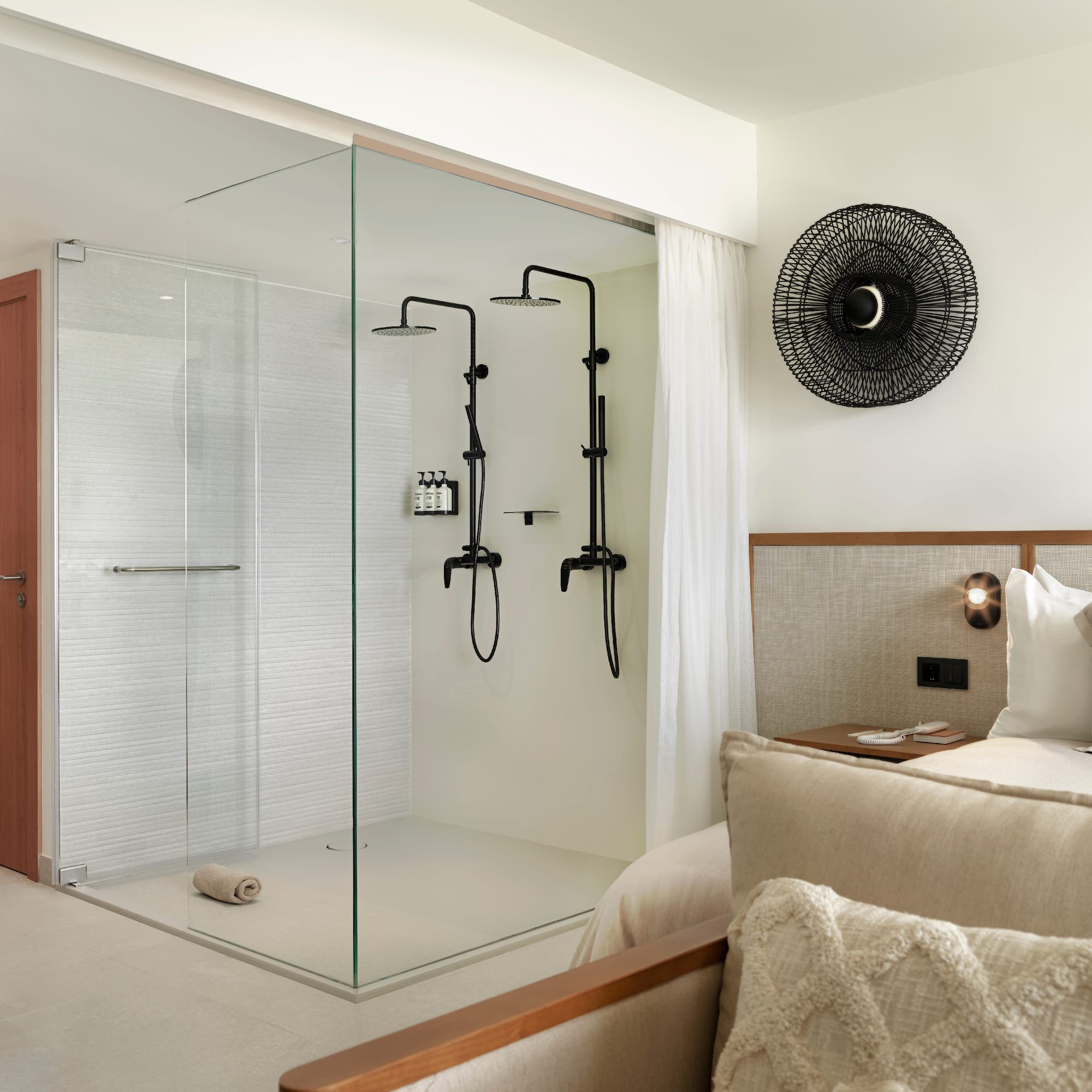 a room with a glass shower and a bed
