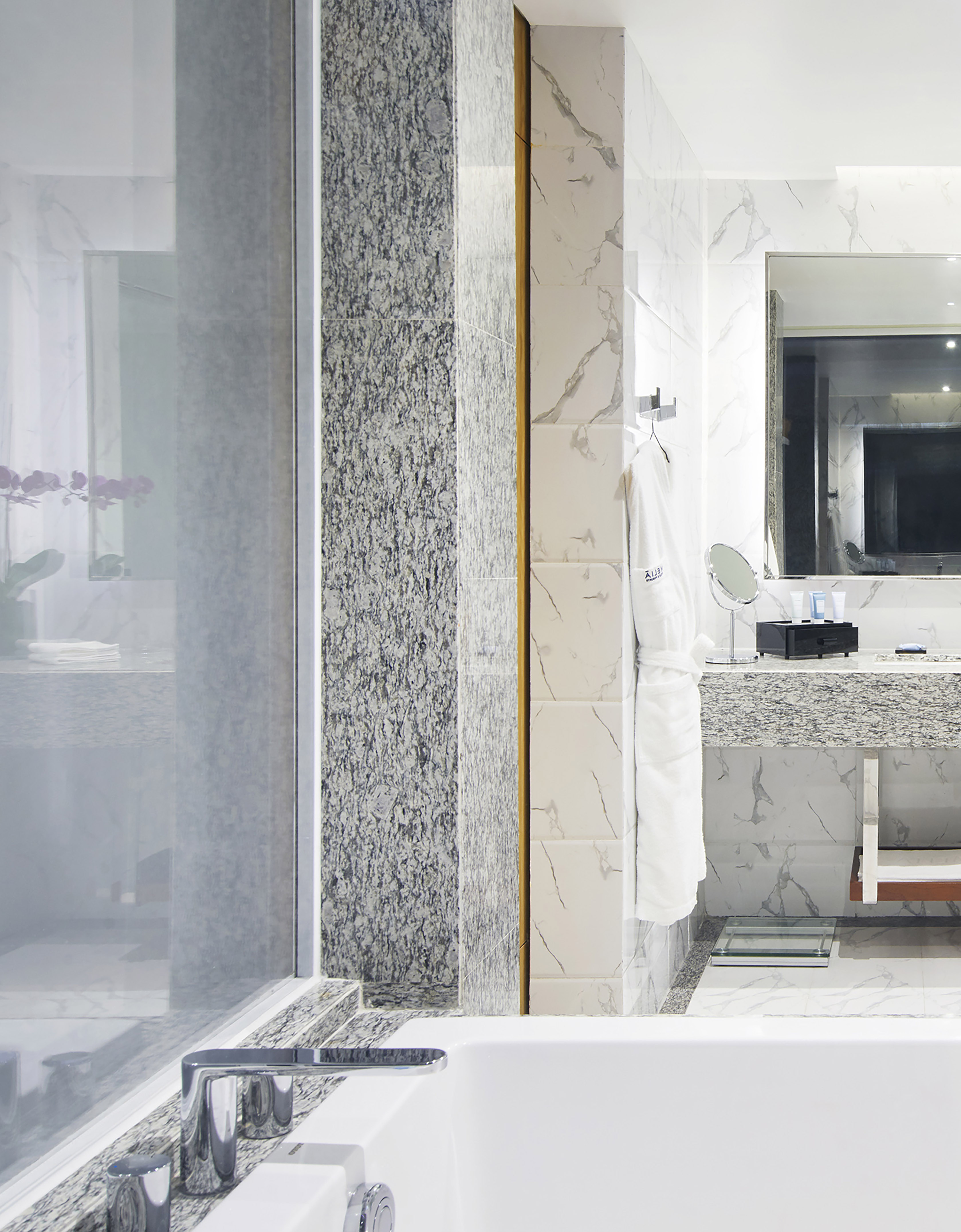 Modern luxury bathroom with marble walls, bathtub, shower, and vanity.