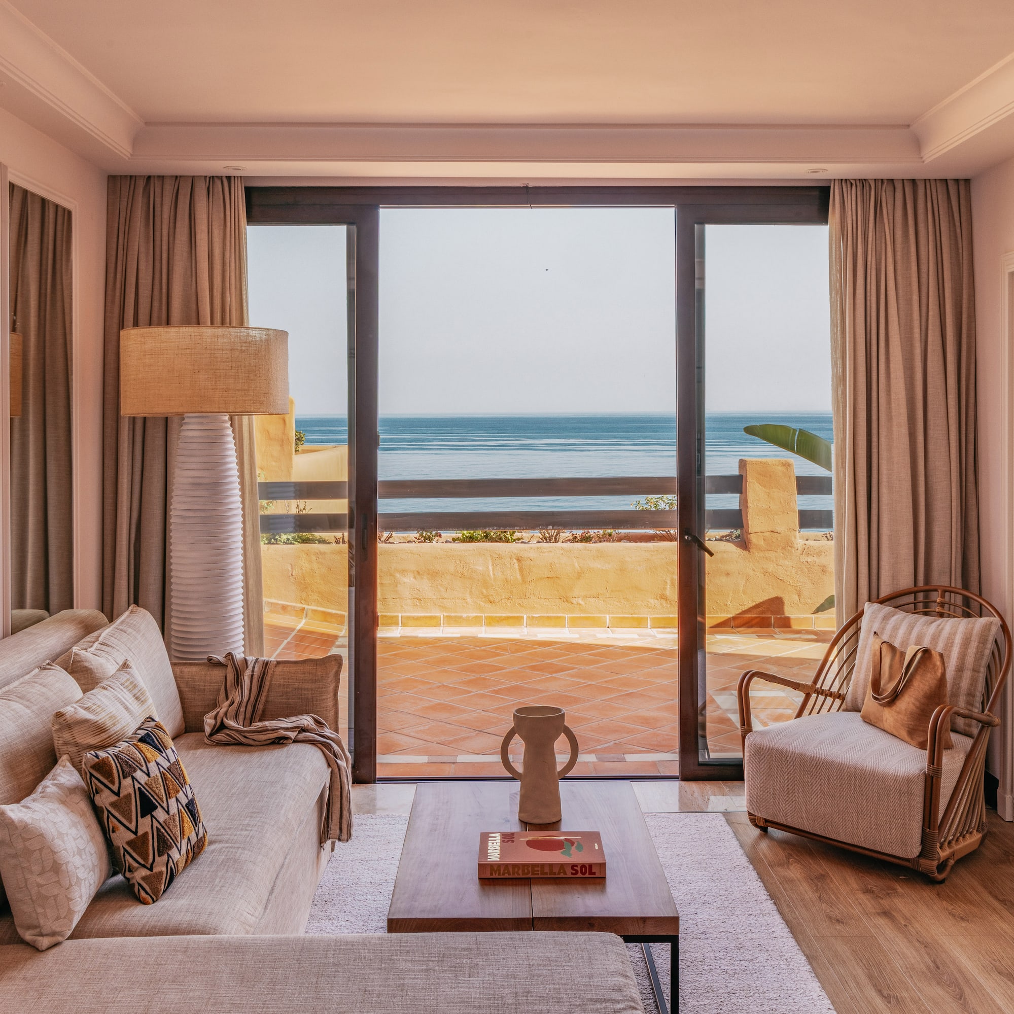 Coastal living room with ocean view, sofa, coffee table, and balcony.