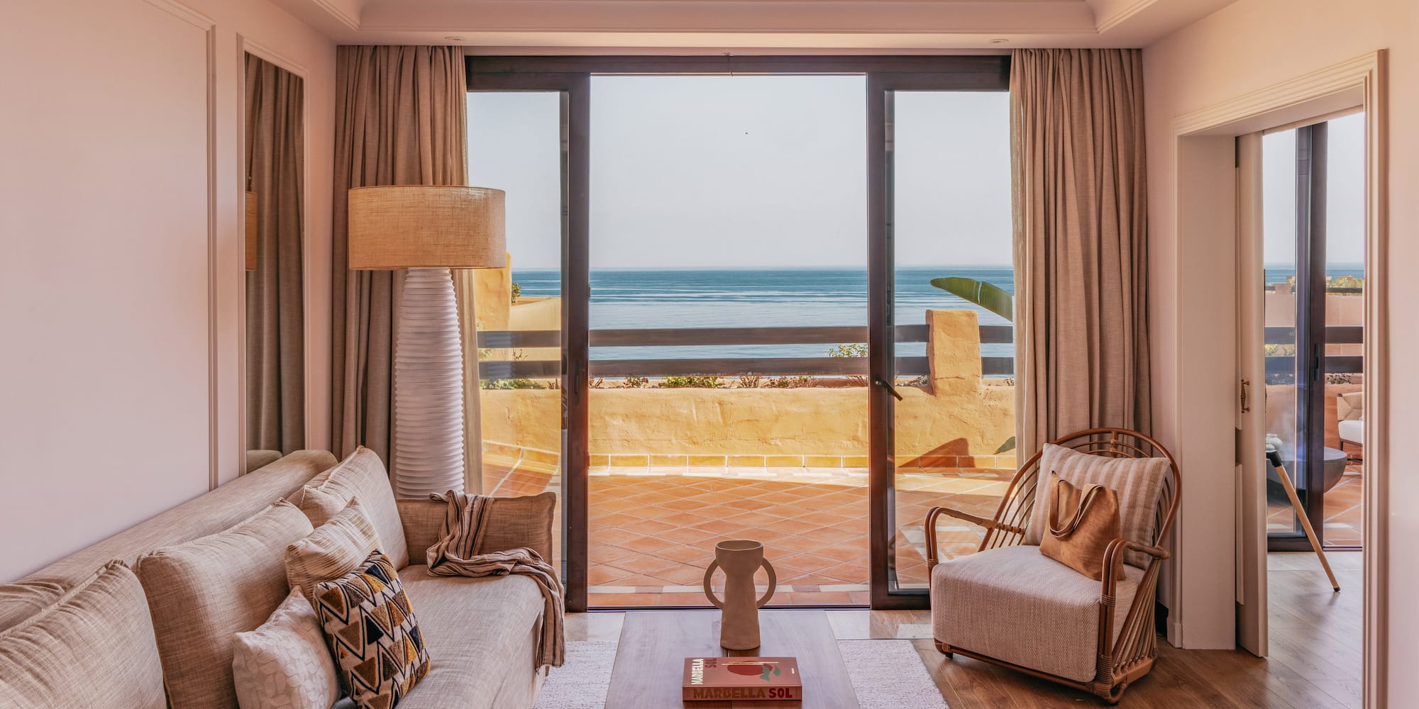 Marbella ocean view living room with sofa, armchair, and balcony.