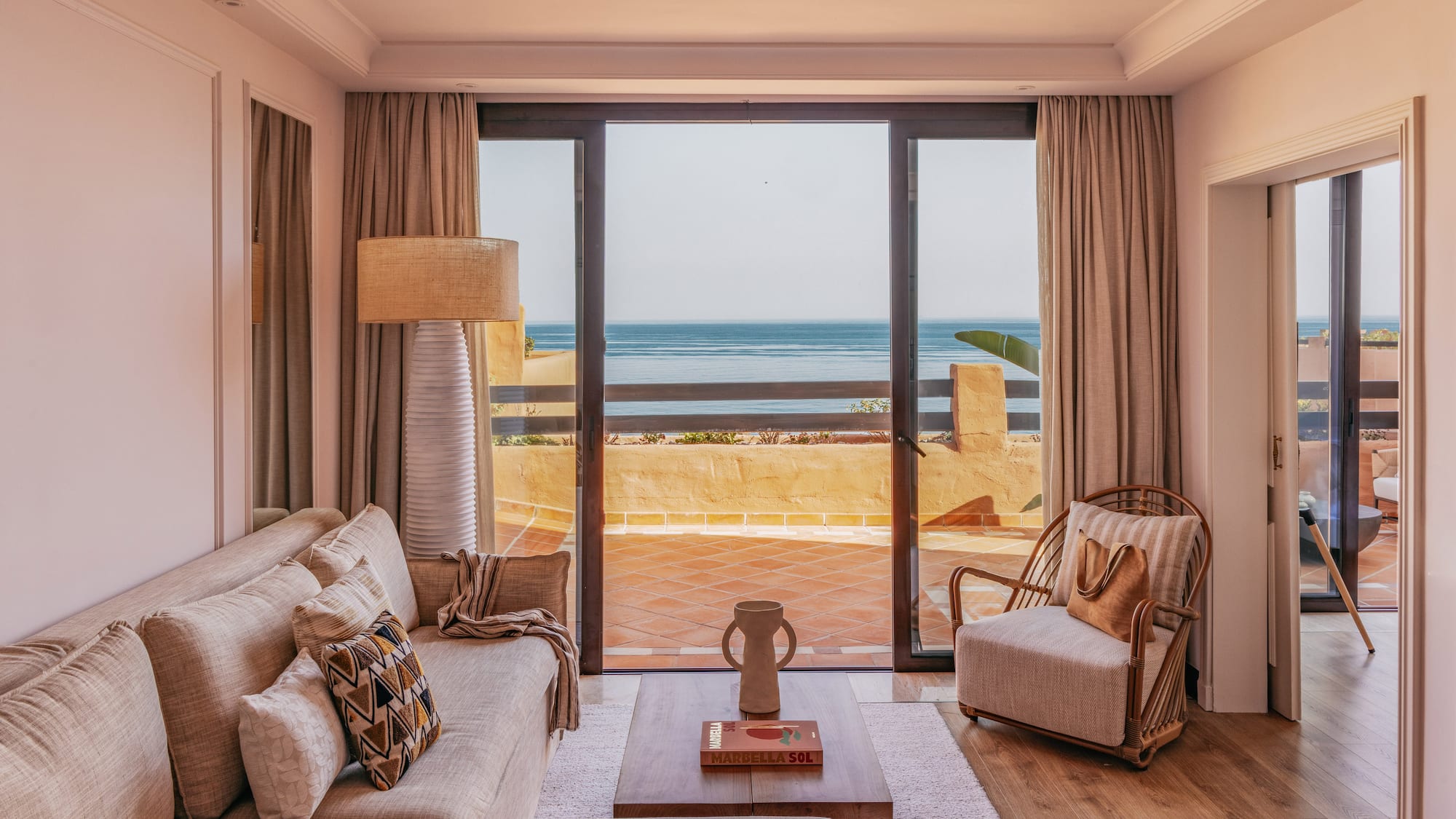 Marbella ocean view living room with sofa, armchair, and balcony.