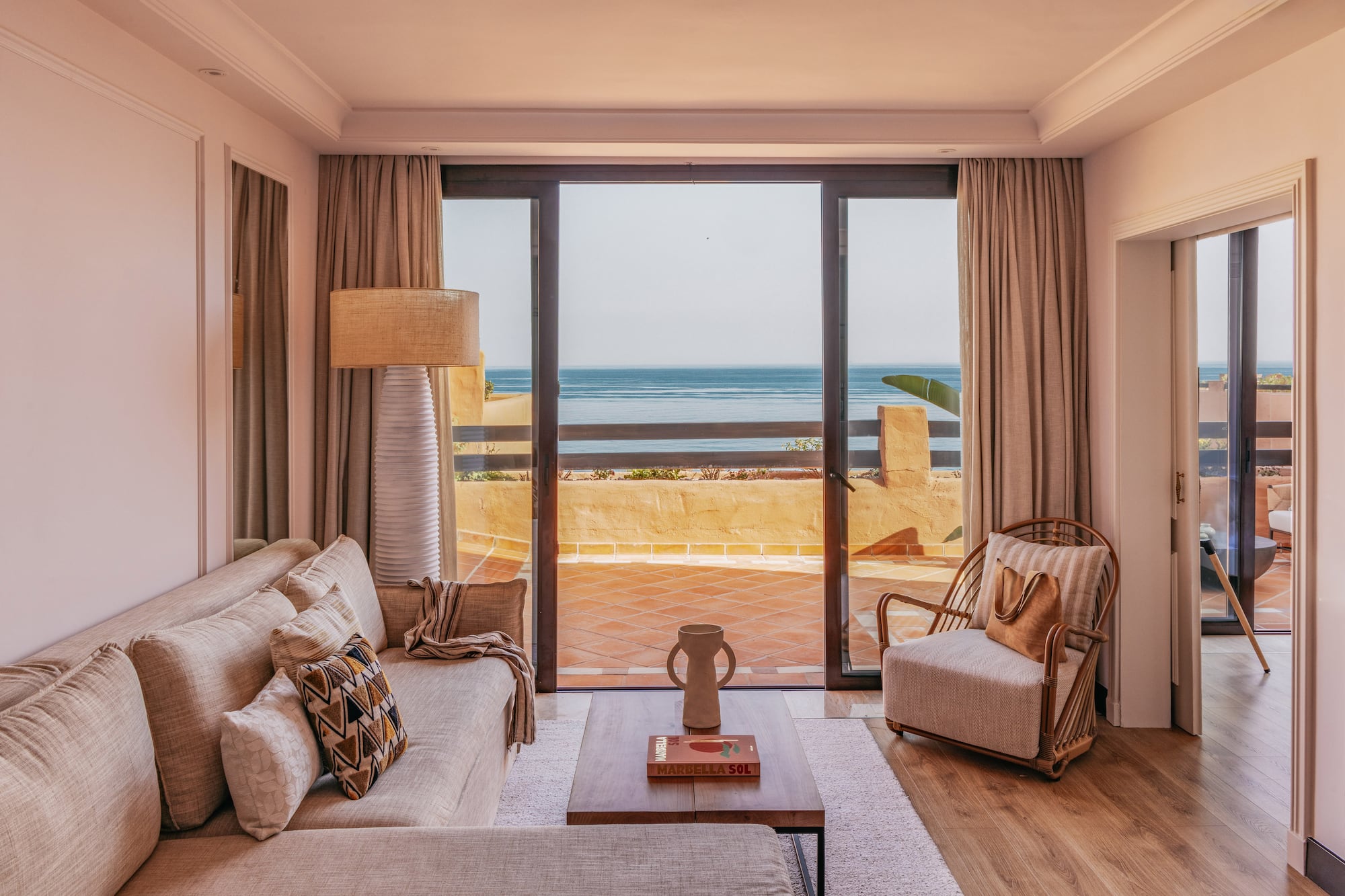 Marbella ocean view living room with sofa, armchair, and balcony.
