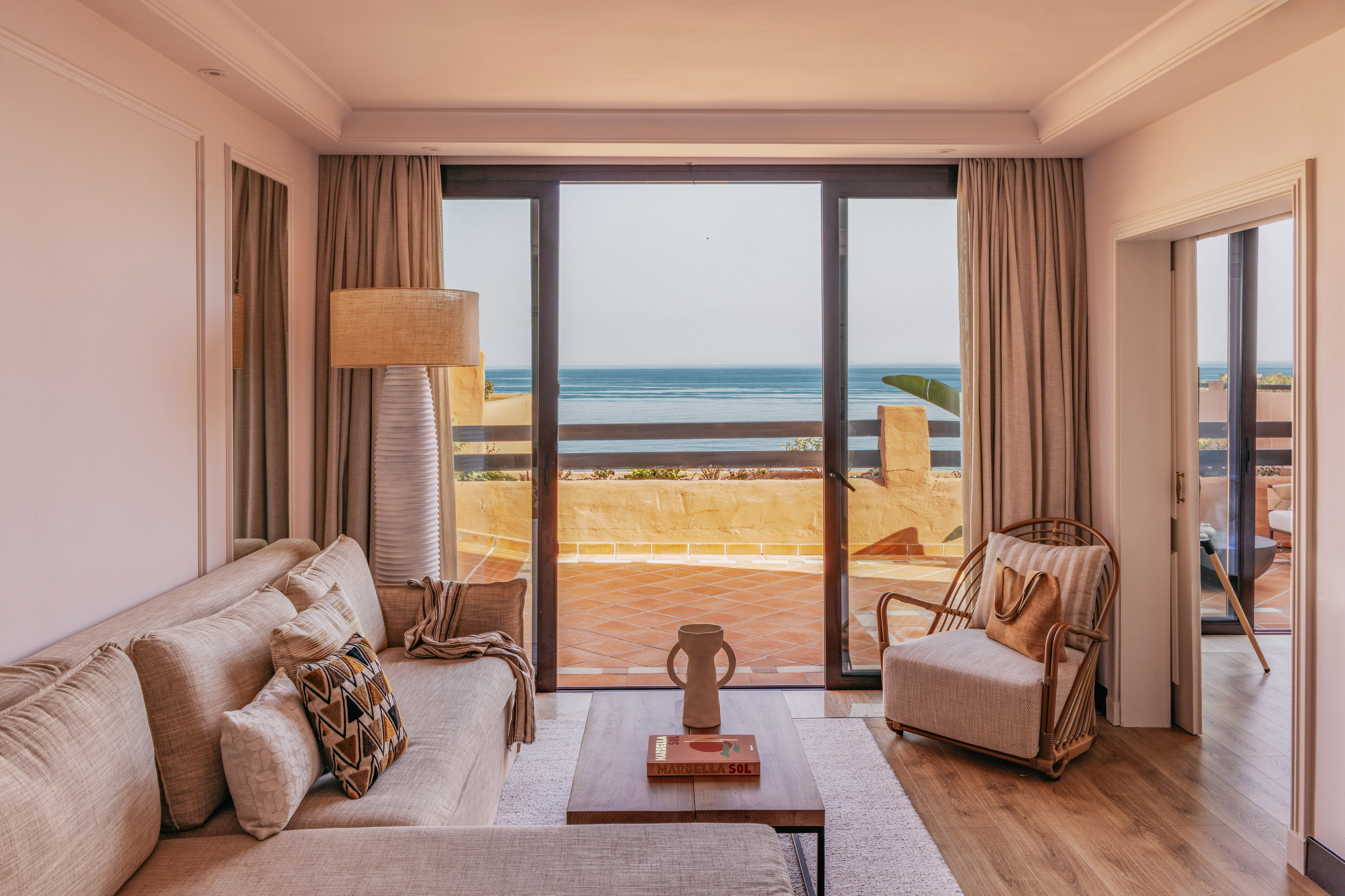 Marbella ocean view living room with sofa, armchair, and balcony.