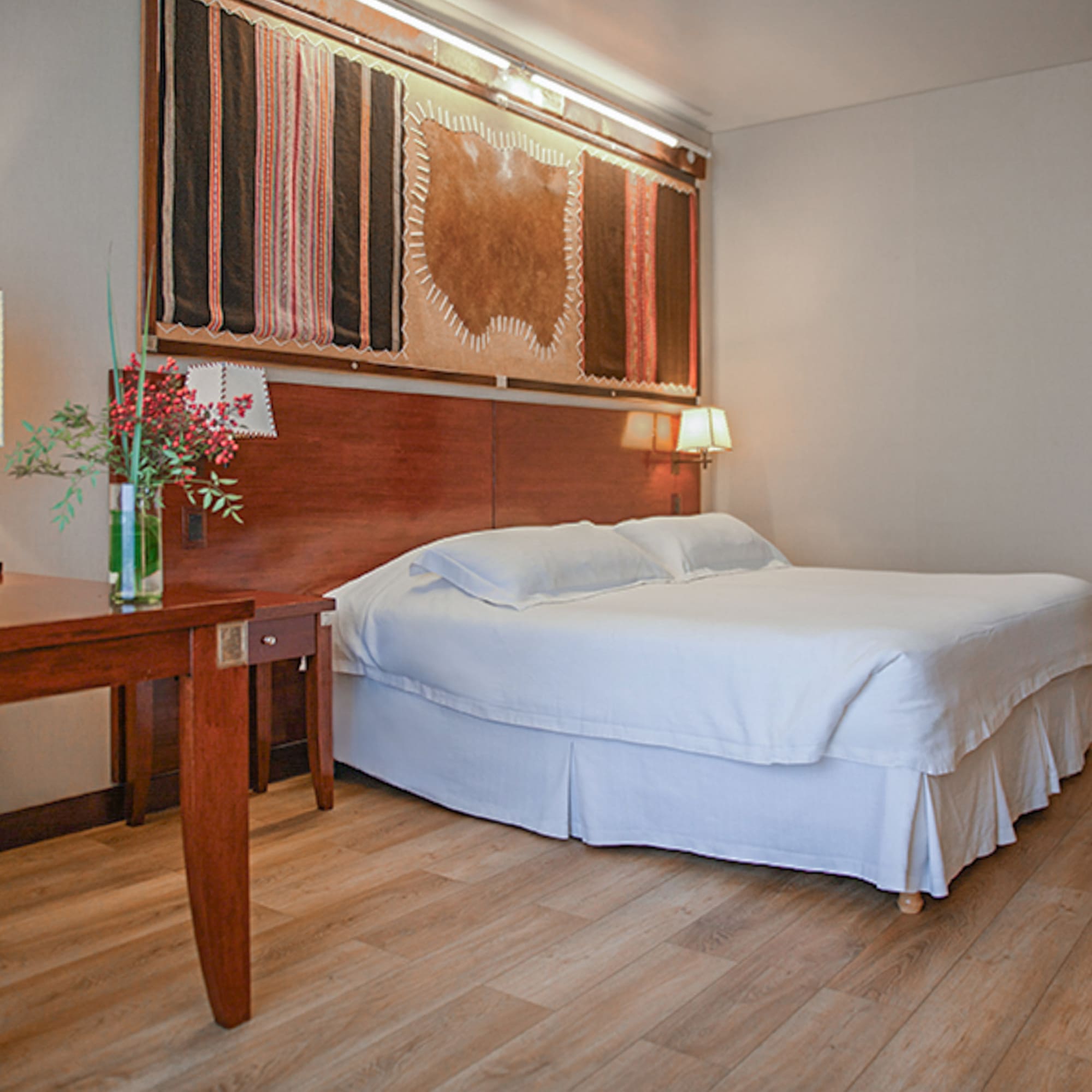 a bed with a wood headboard and a table with a vase of flowers