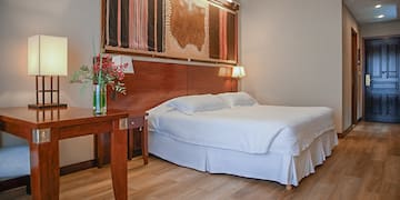 a bed with a wood headboard and a table with a vase of flowers