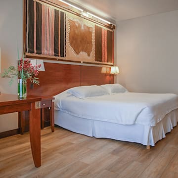 a bed with a wood headboard and a table with a vase of flowers