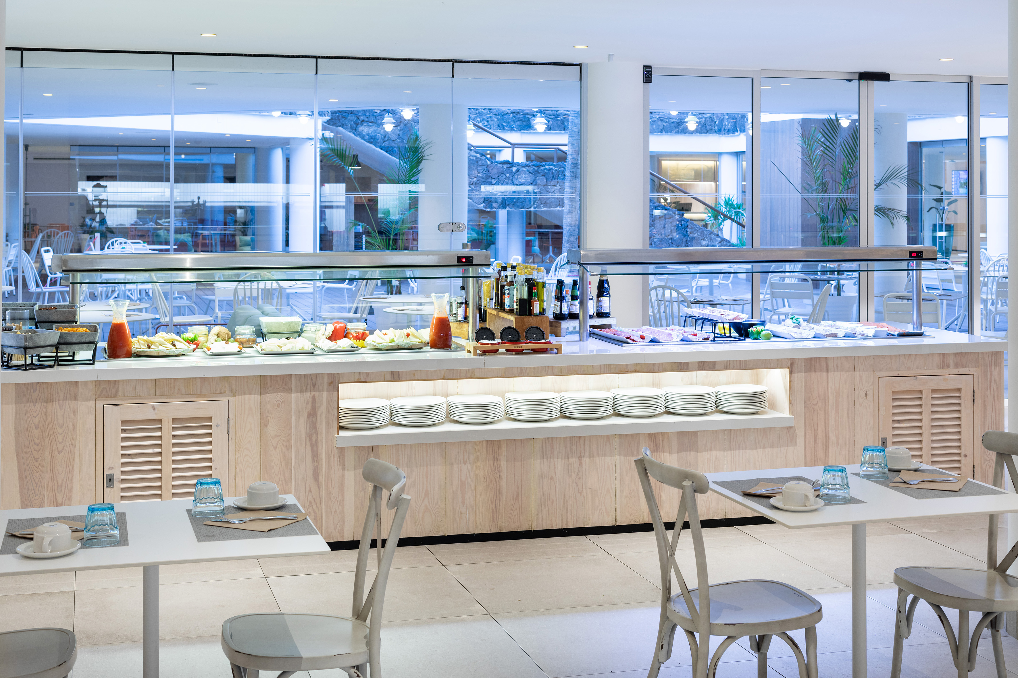 Hotel buffet with fresh breakfast, juices, and neatly set dining tables.