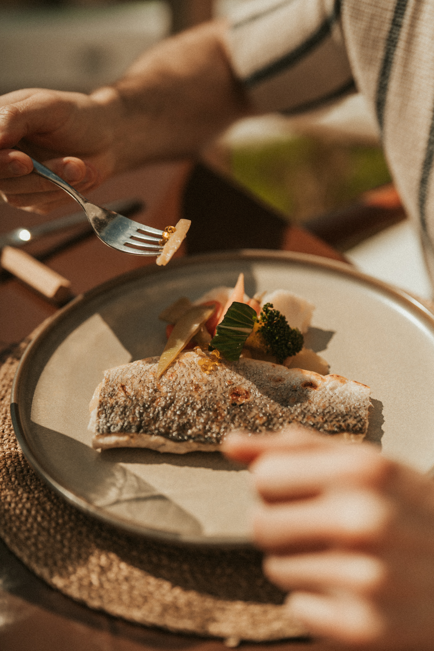 Dining on cooked fish with crispy skin, fresh vegetables, and golden roe.