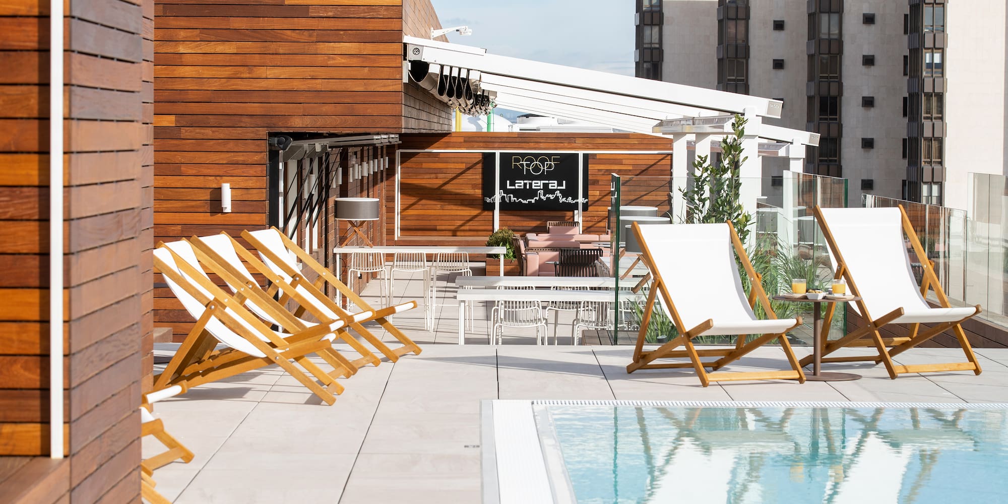 a pool with chairs and tables on a rooftop