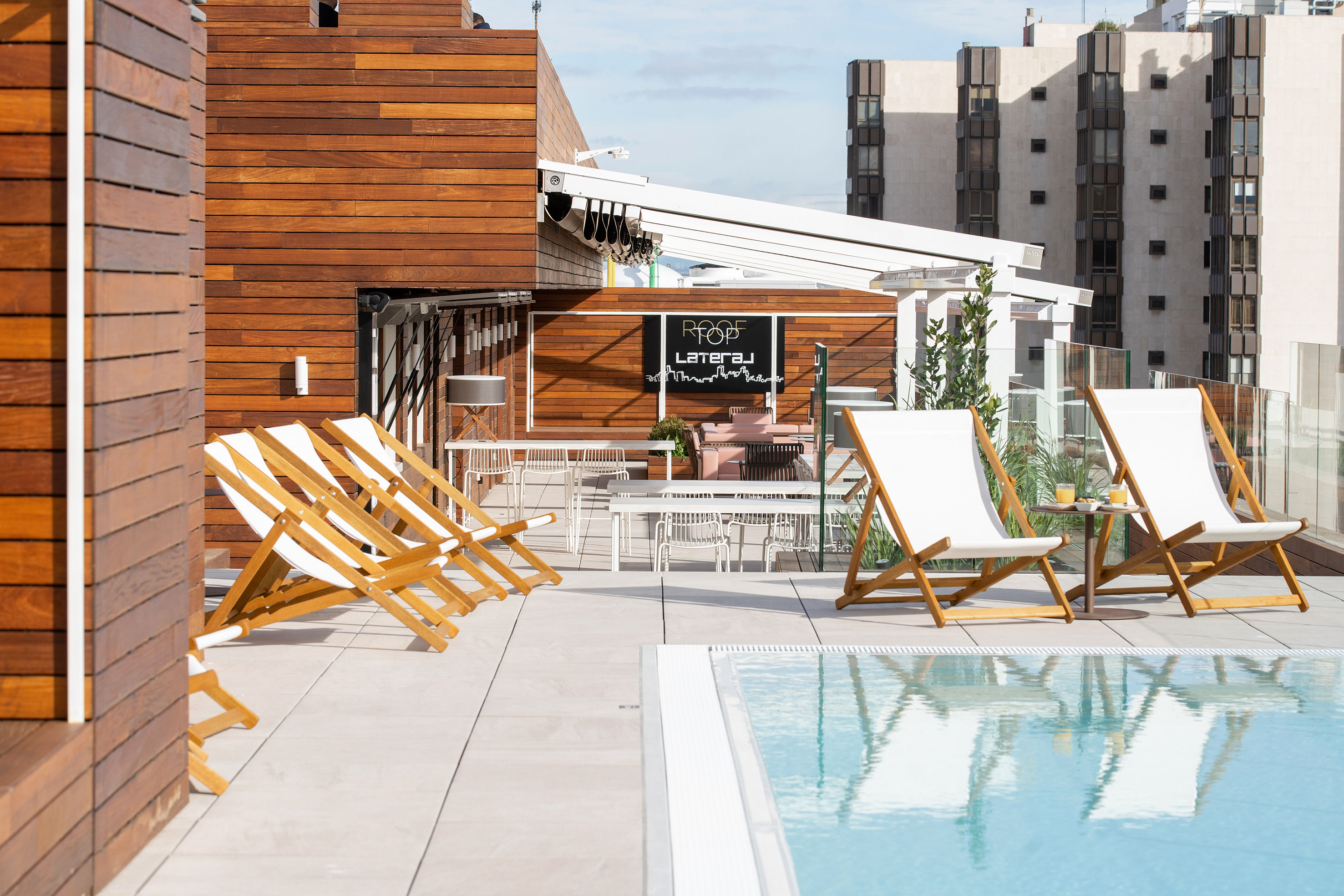 Modern rooftop bar with pool, wood paneling, and lounge chairs.