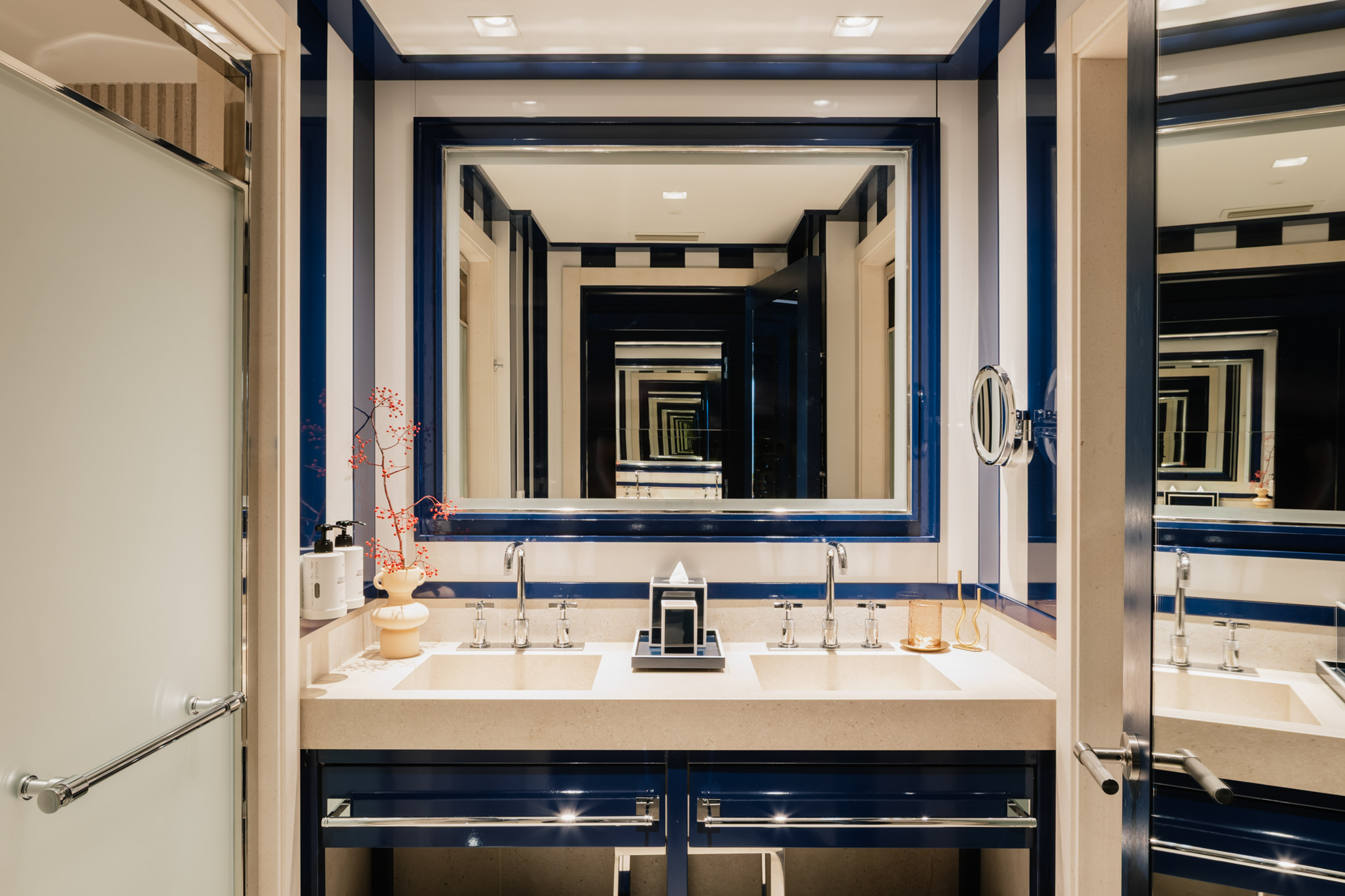 Blue and white striped bathroom, double vanity, infinite mirror view.
