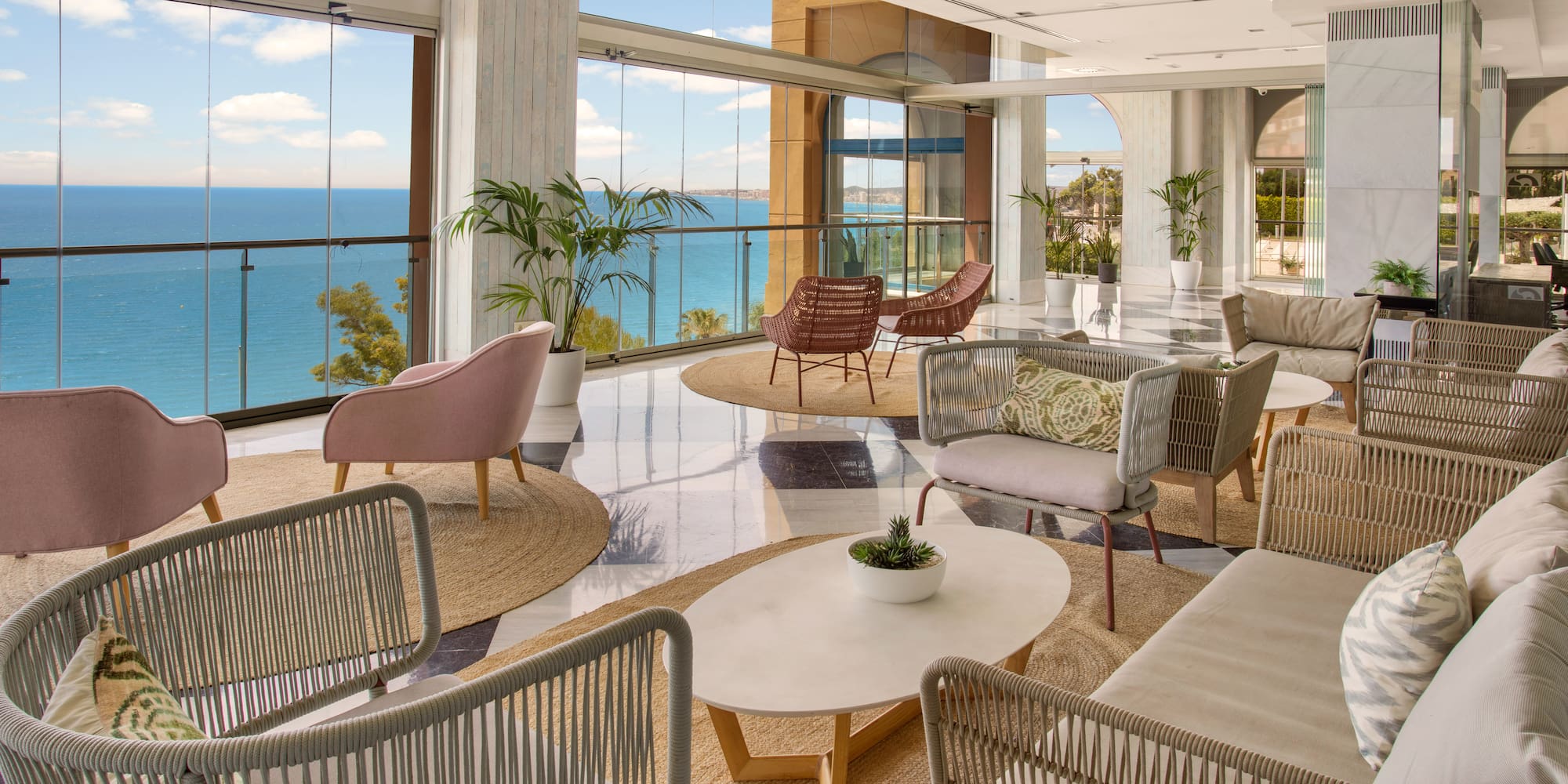 Modern hotel lounge with panoramic sea view, stylish seating, and natural light.