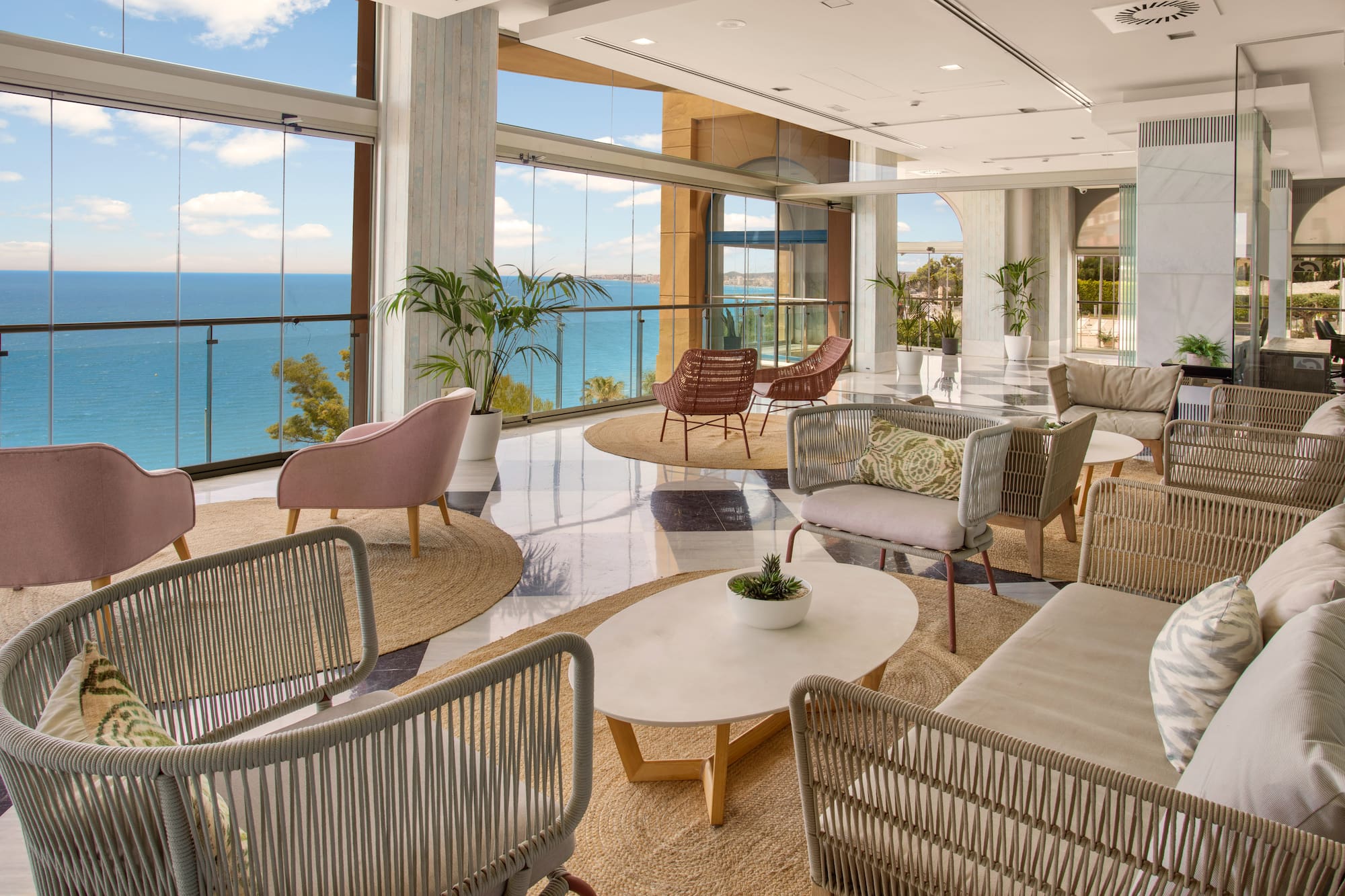 Modern hotel lounge with panoramic sea view, stylish seating, and natural light.